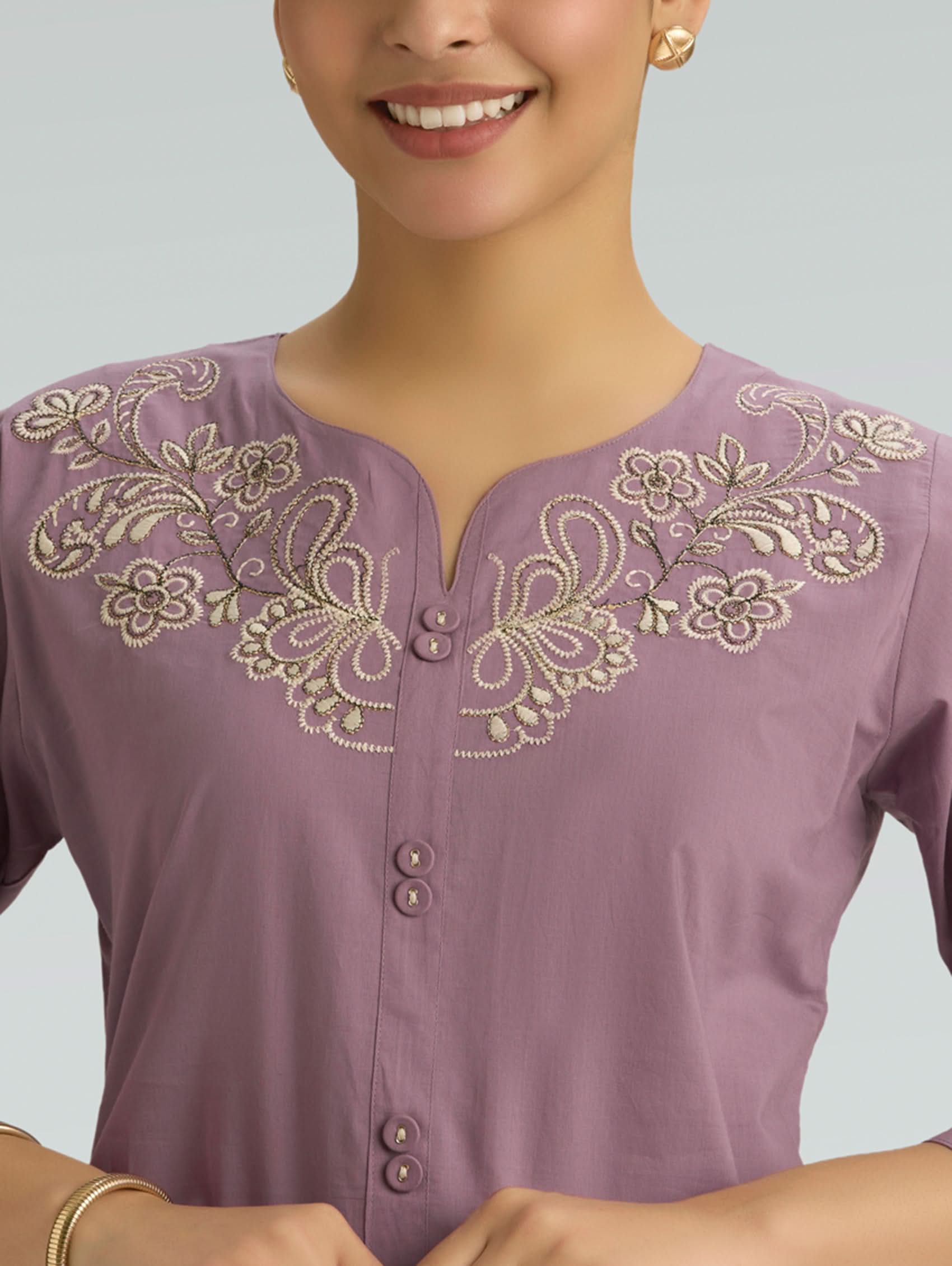 Purple top with gold embroidery on a plain background