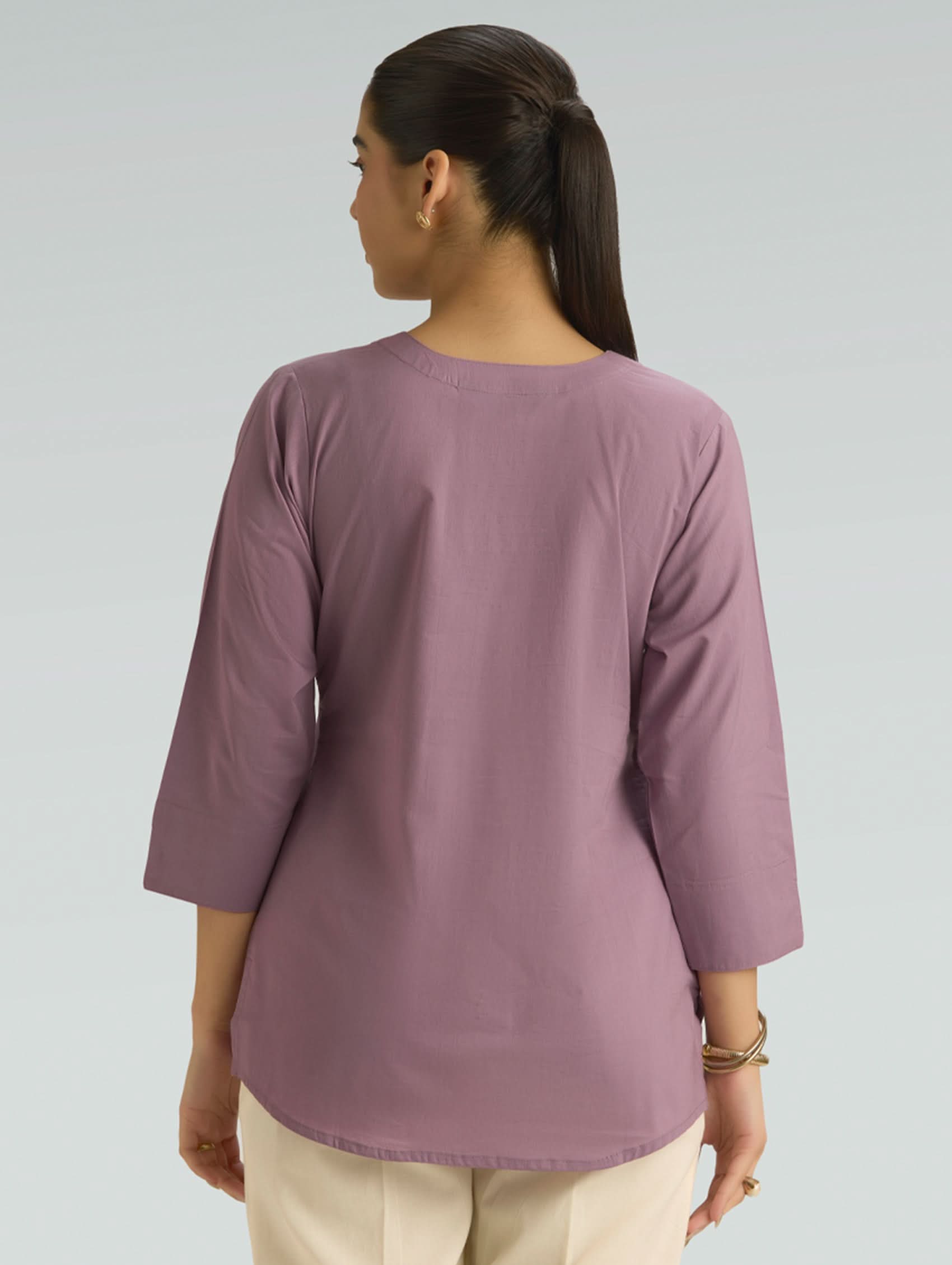 Person wearing a purple shirt with three-quarter sleeves on a plain background