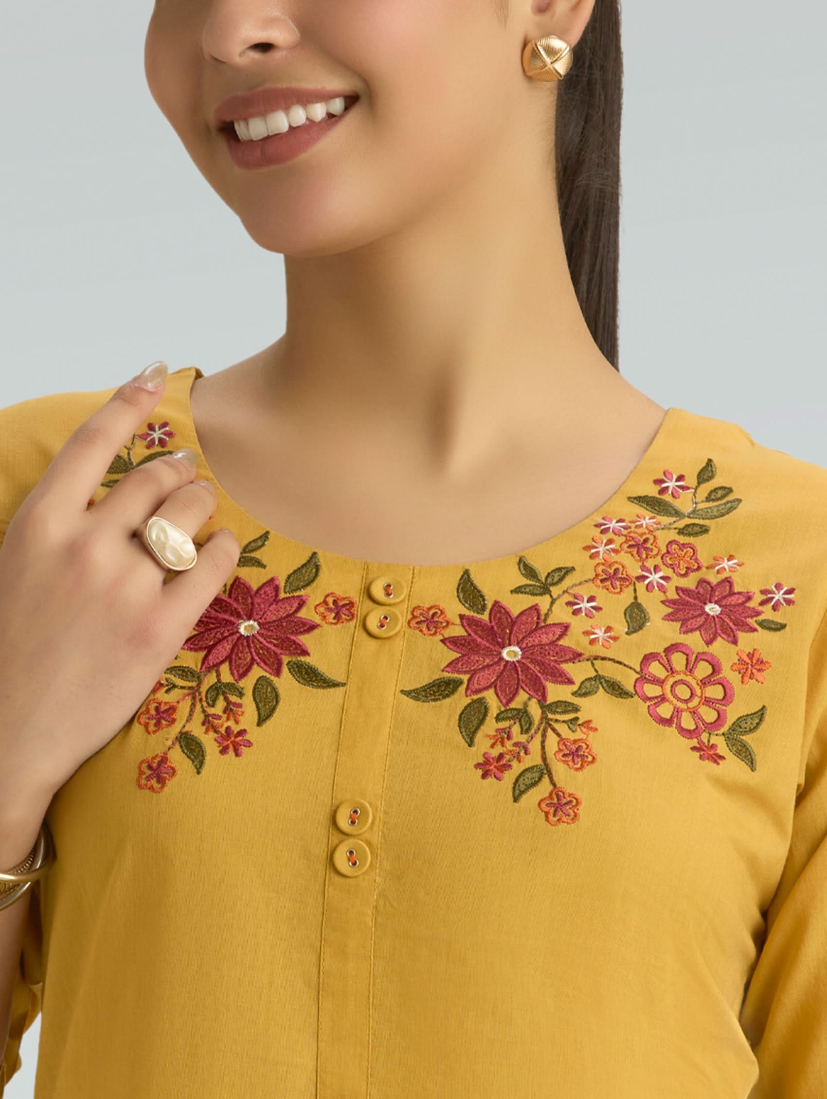 Yellow top with floral embroidery on a plain background