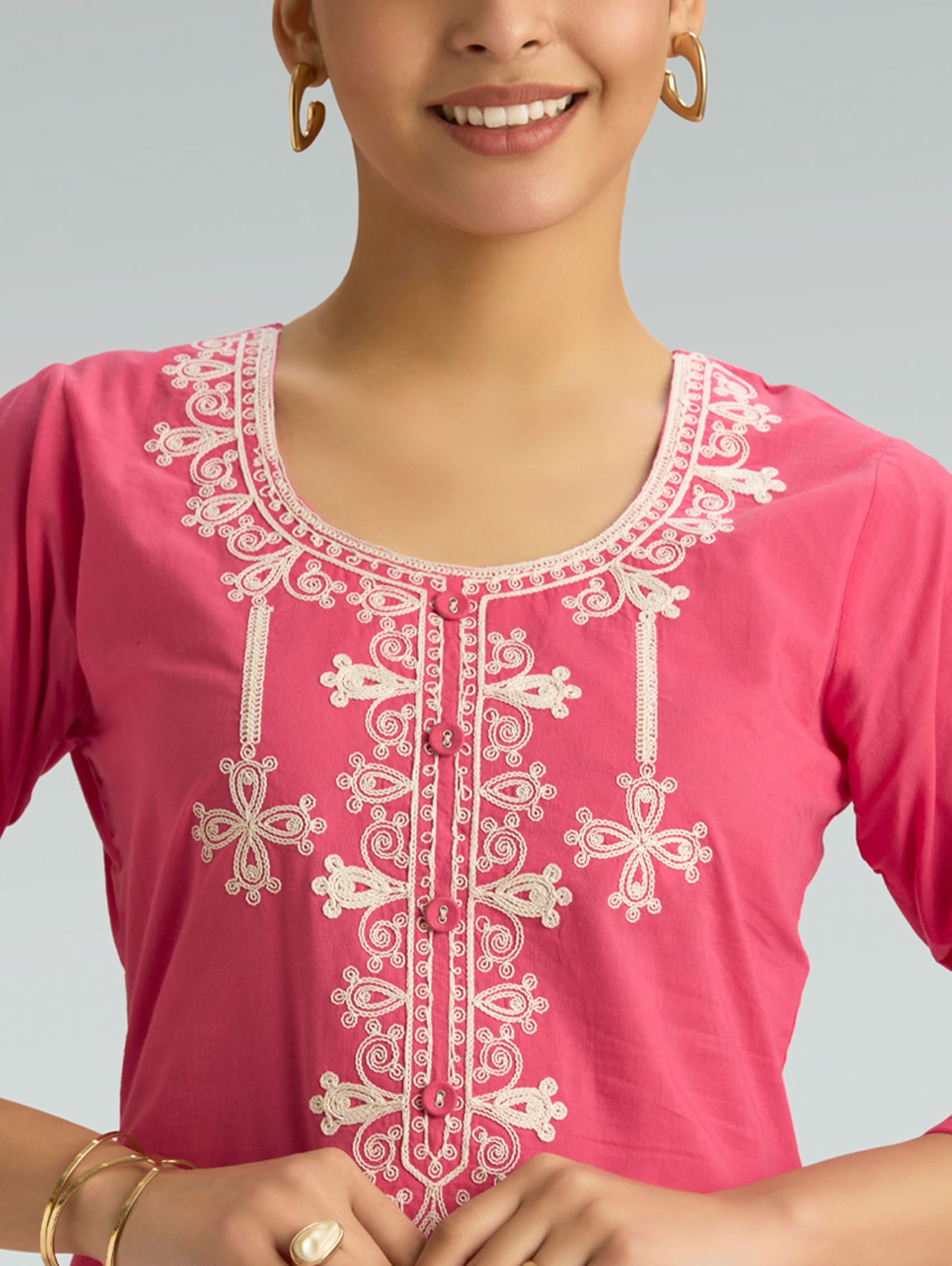 Pink top with white embroidery on a gray background