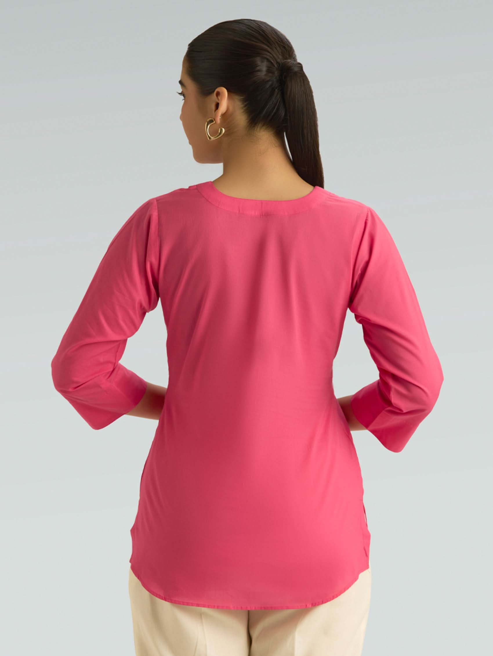 Person wearing a pink long-sleeve top on a gray background