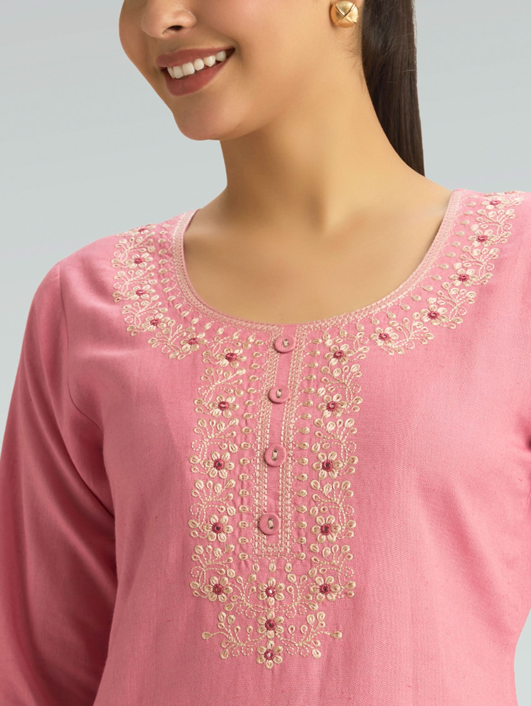 Close-up of a pink embroidered garment with a gray background