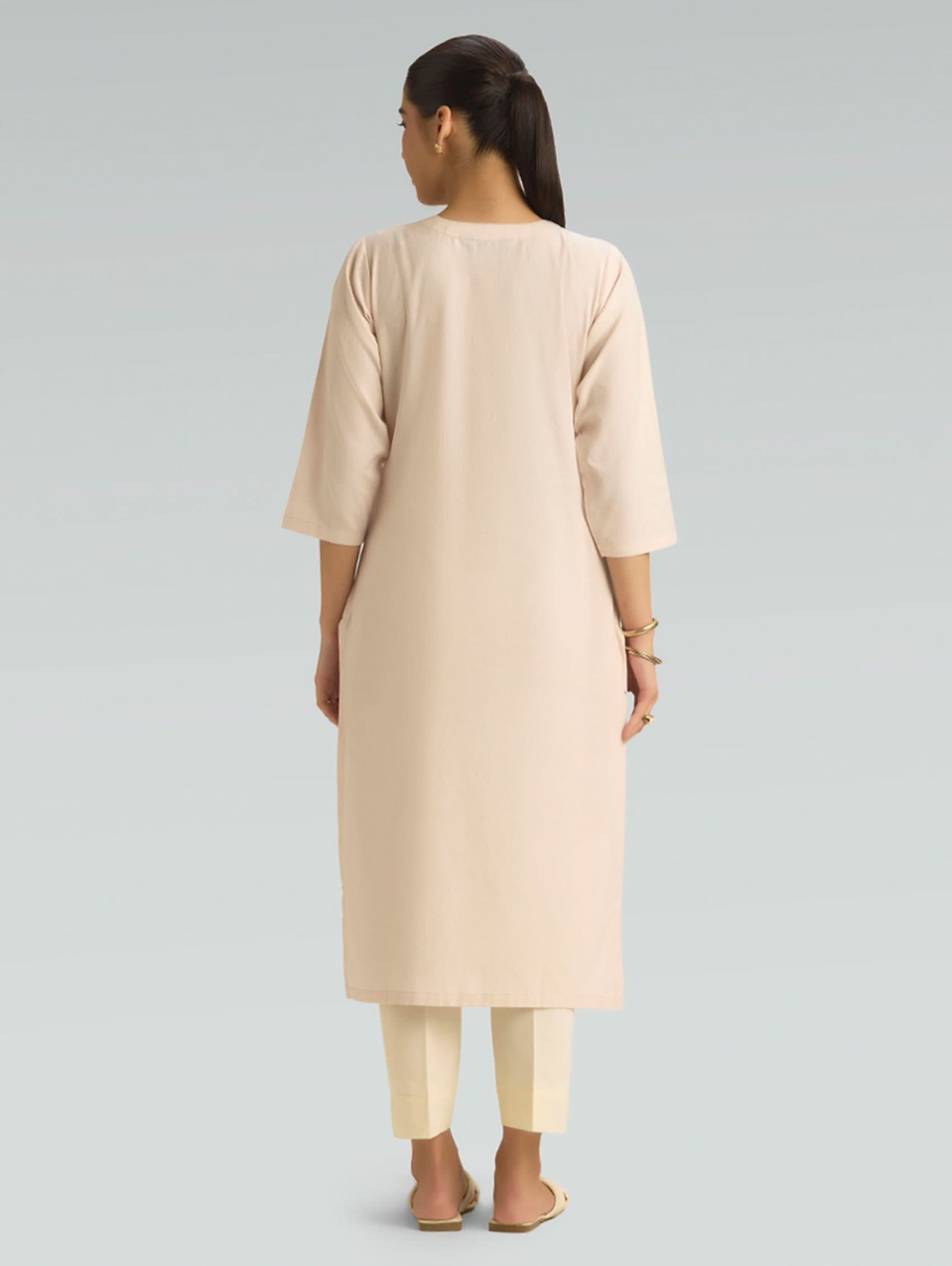Woman wearing a beige long dress on a gray background