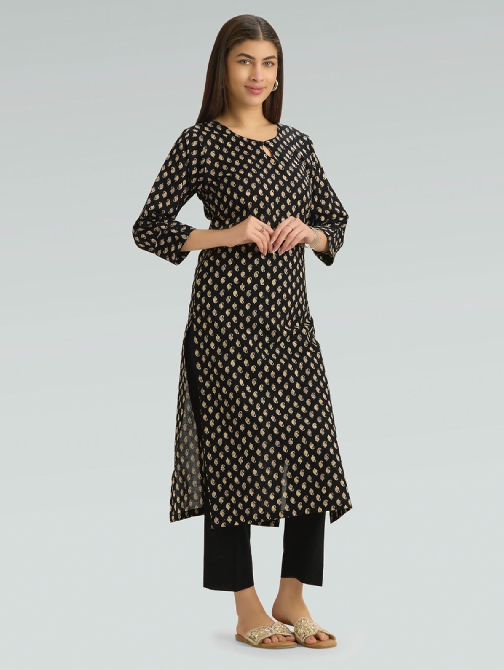 Woman wearing a black and white patterned kurta with black pants on a light gray background
