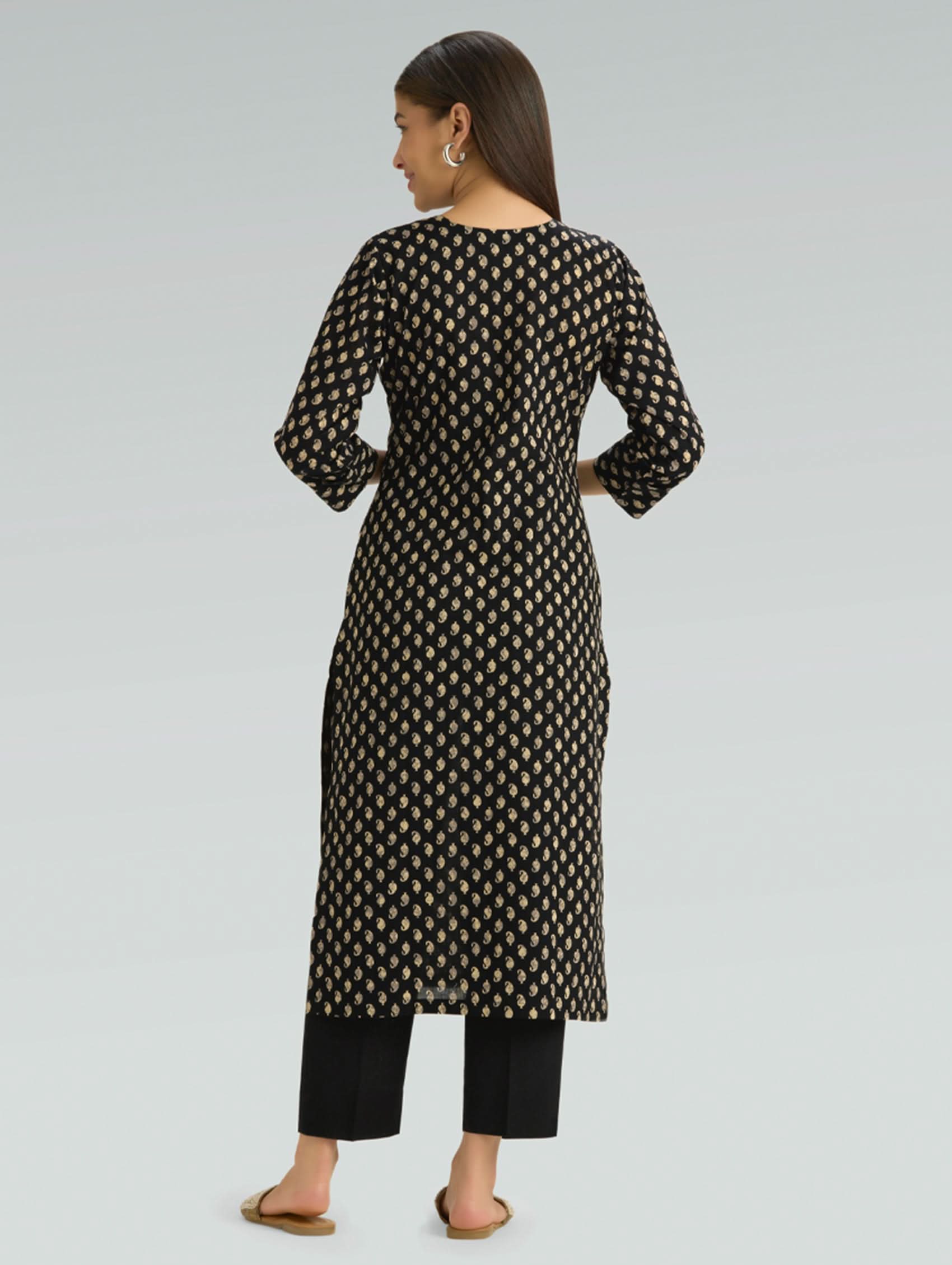 Woman wearing a black and white patterned kurta with black pants on a light gray background