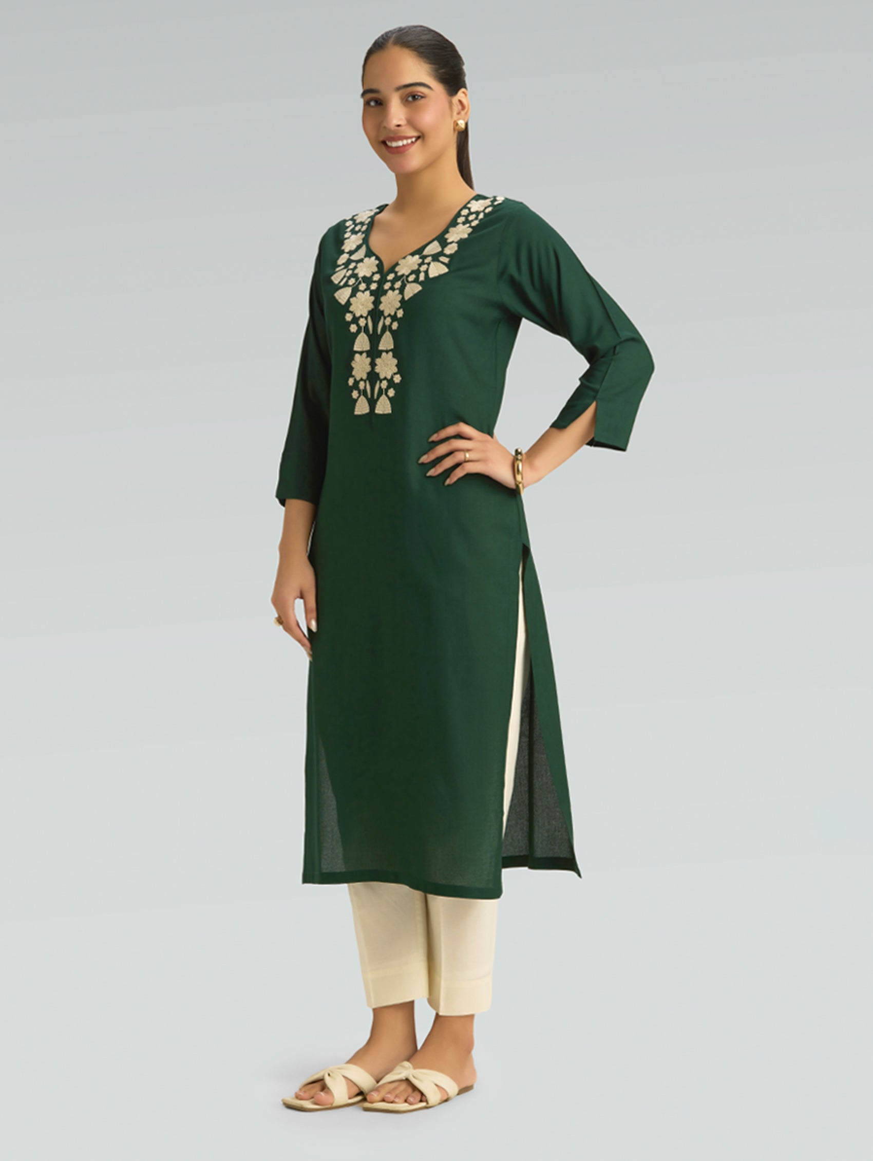 Woman wearing a green kurta with white embroidery on a gray background
