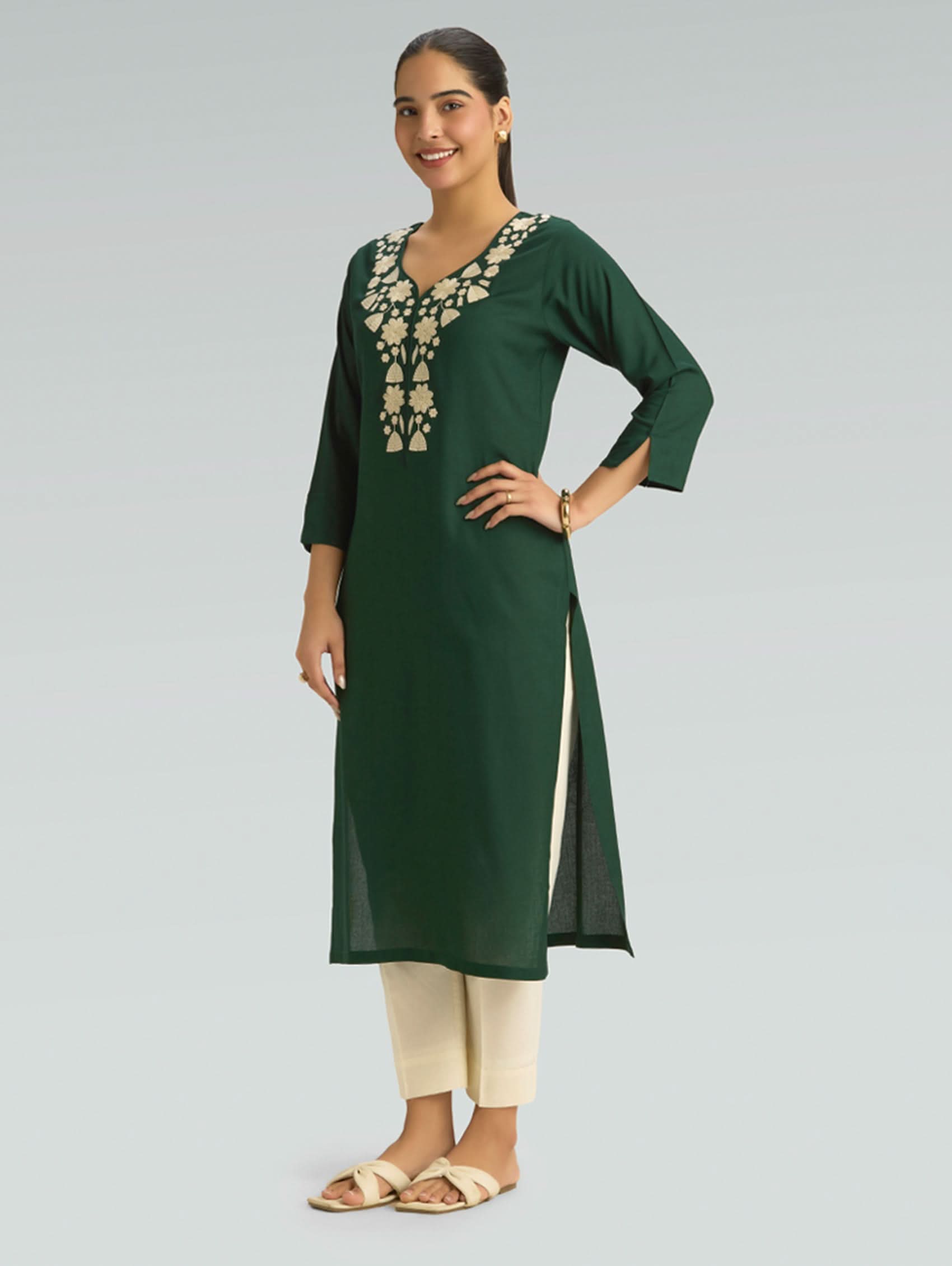 Woman wearing a green kurta with white embroidery on a gray background