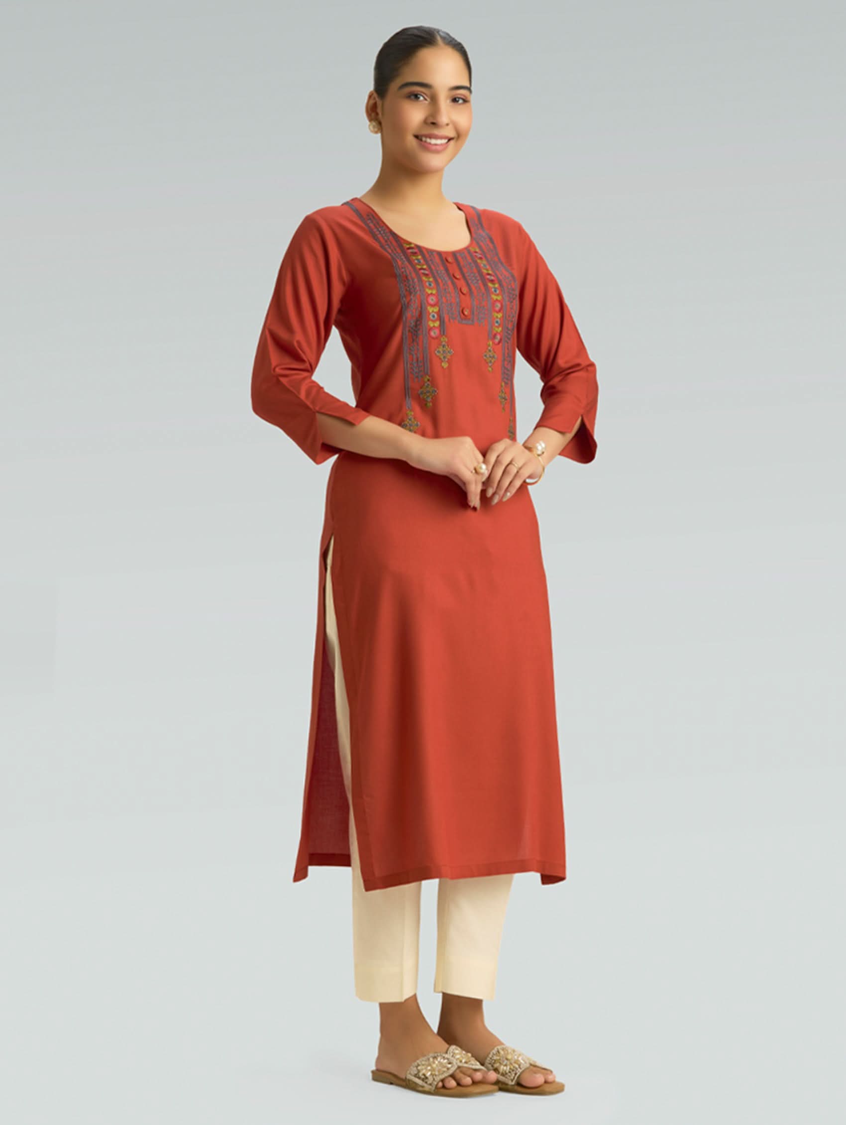 Woman wearing a red kurta with white pants on a light gray background