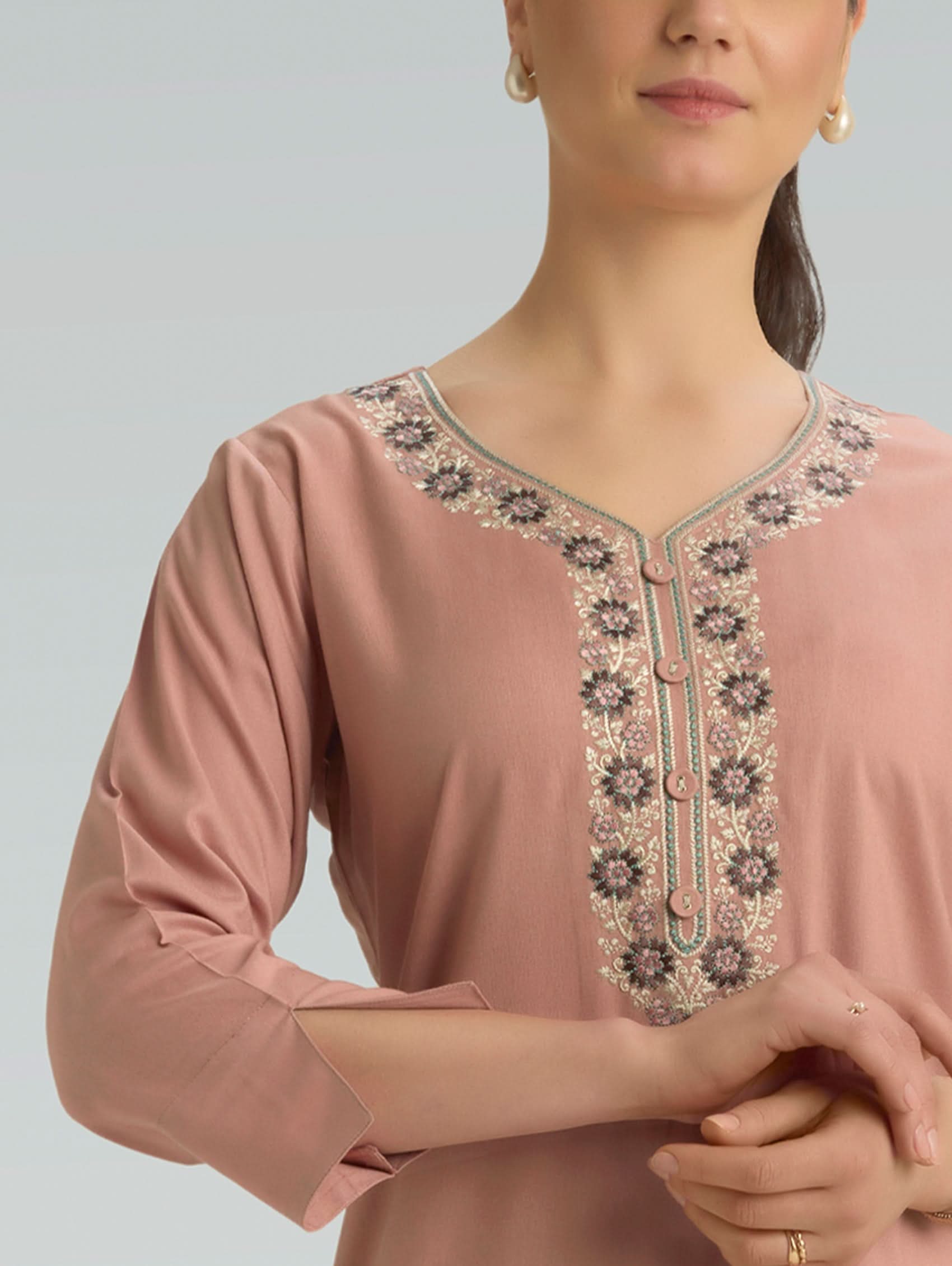 Pink blouse with intricate embroidery on a light gray background