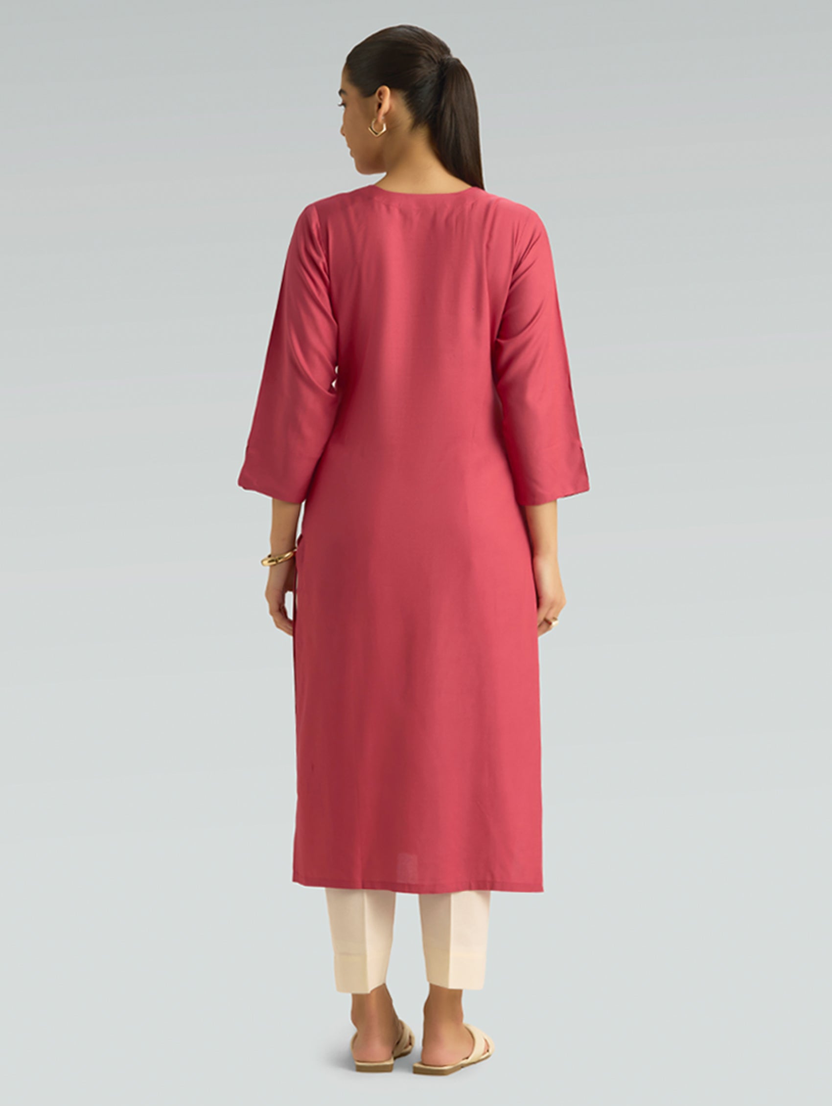 A woman in a straight-fit pink kurta with a round neckline, adorned with computerized thread embroidery, shown in a back pose against a soft gray background.