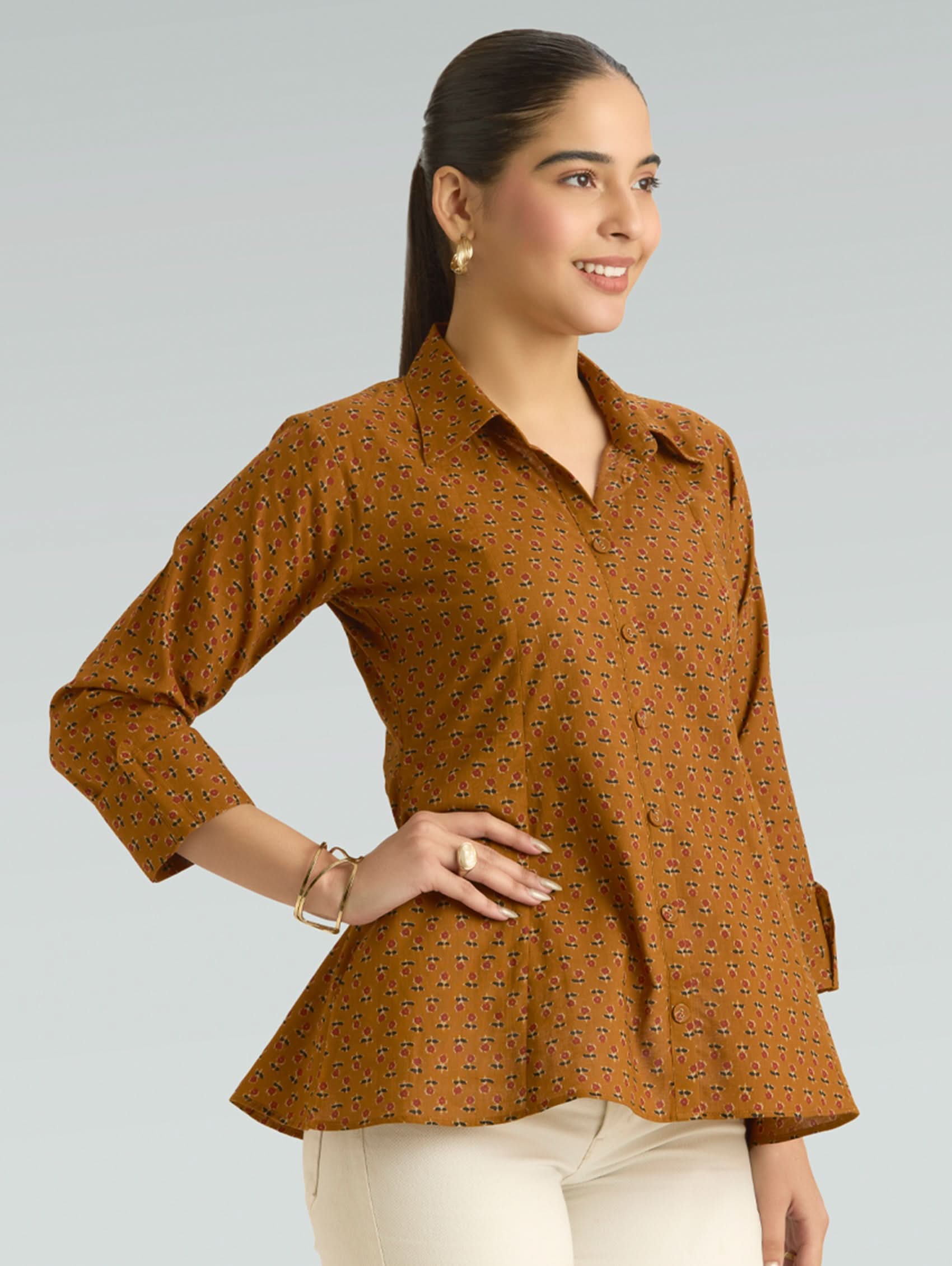 Woman wearing a brown patterned shirt against a gray background