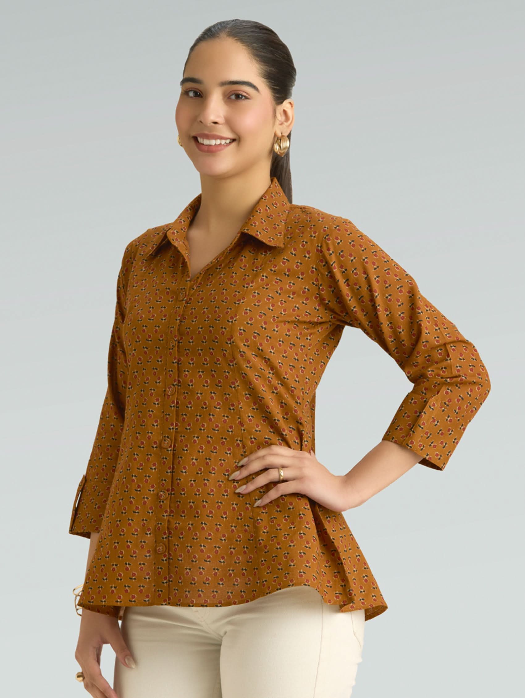 Woman wearing a brown patterned shirt against a gray background