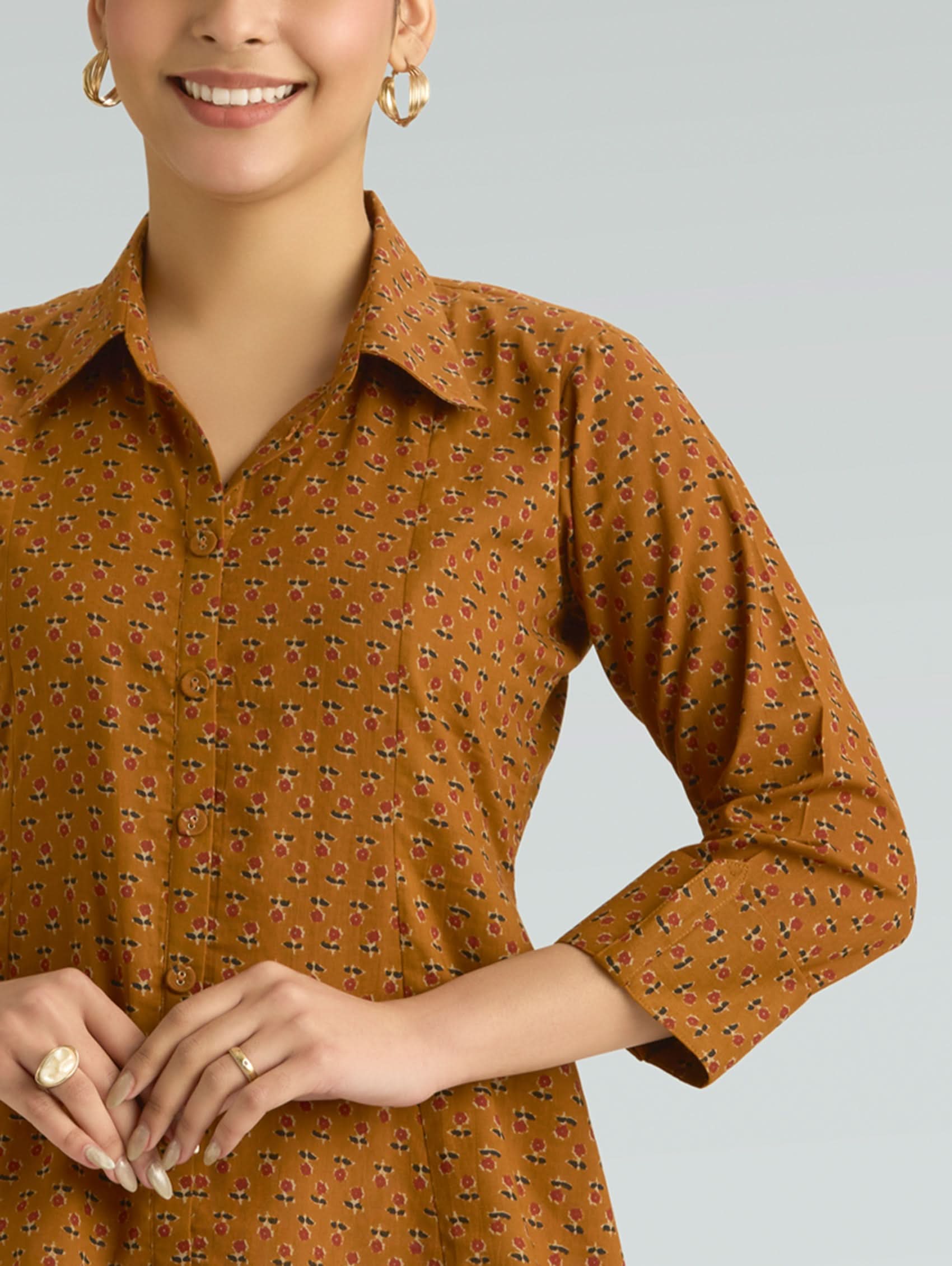 Woman wearing a brown patterned dress against a gray background