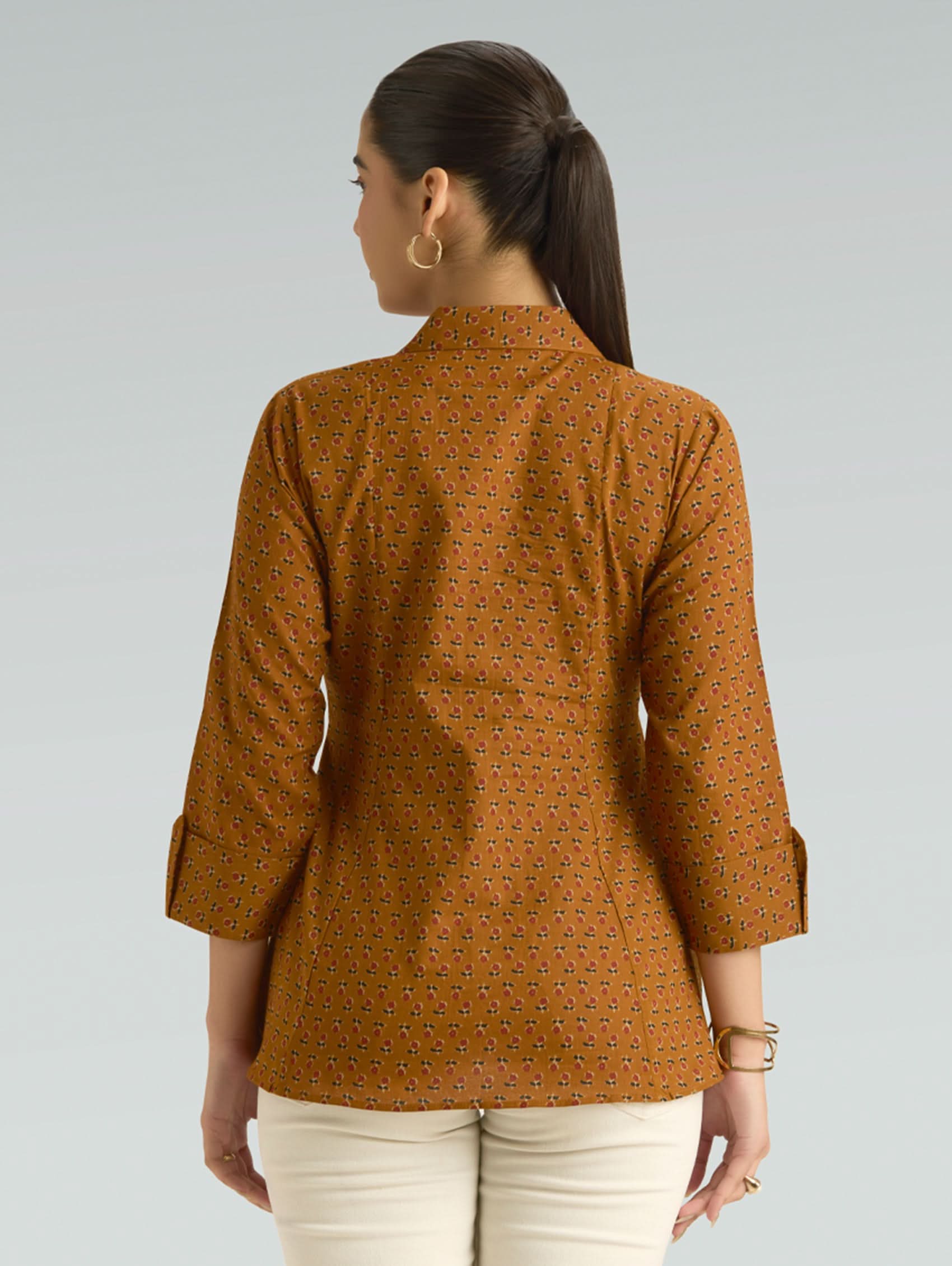 Woman wearing a brown patterned shirt on a gray background