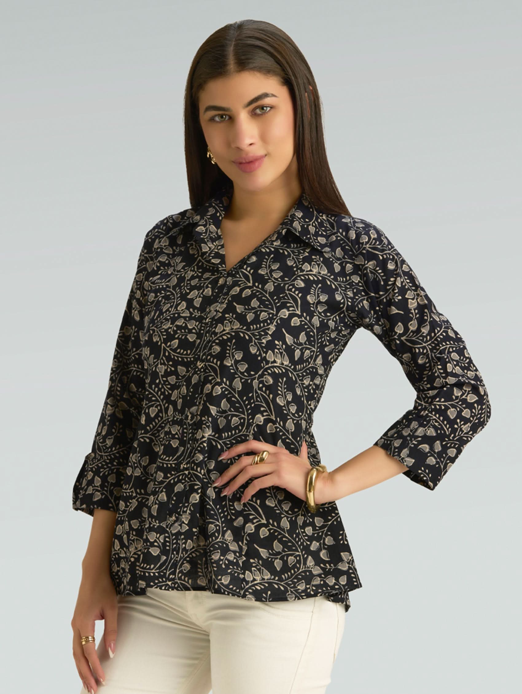 Woman wearing a black floral patterned blouse against a gray background