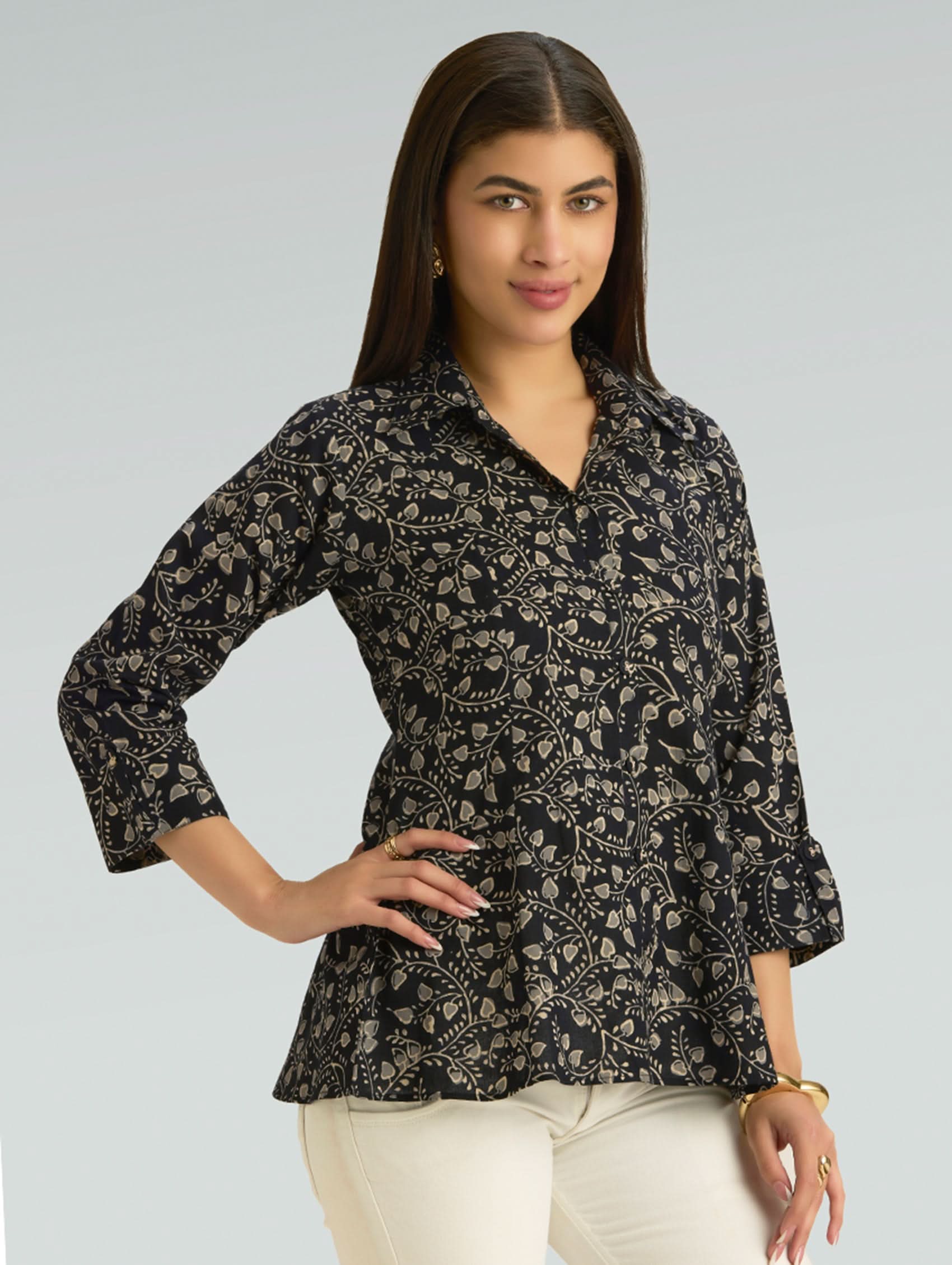 Woman wearing a black floral patterned shirt against a gray background