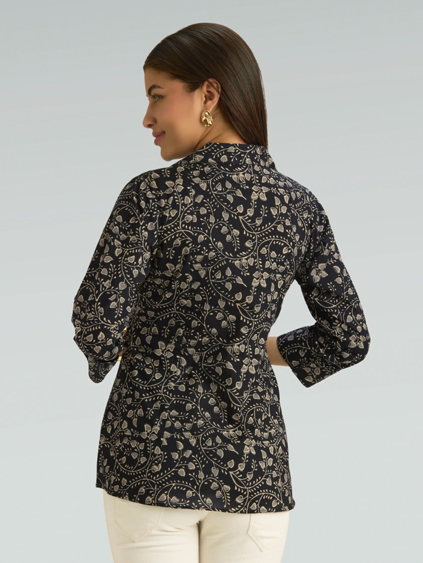 Woman wearing a black floral patterned shirt on a gray background