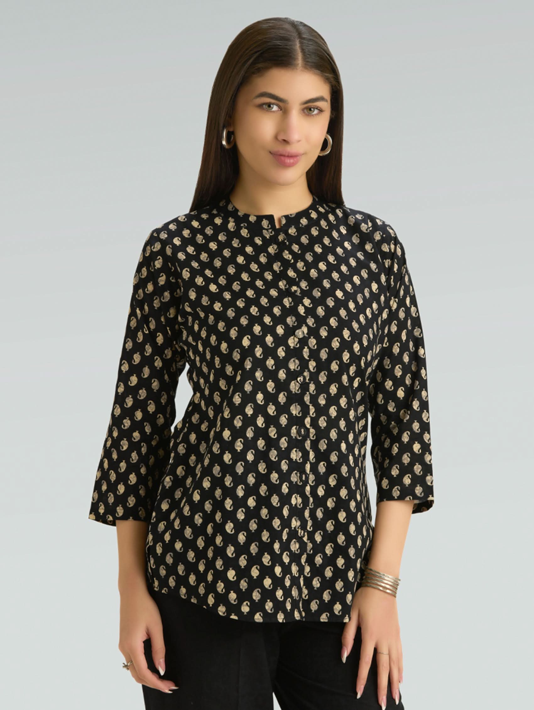 Woman wearing a black floral patterned top on a gray background