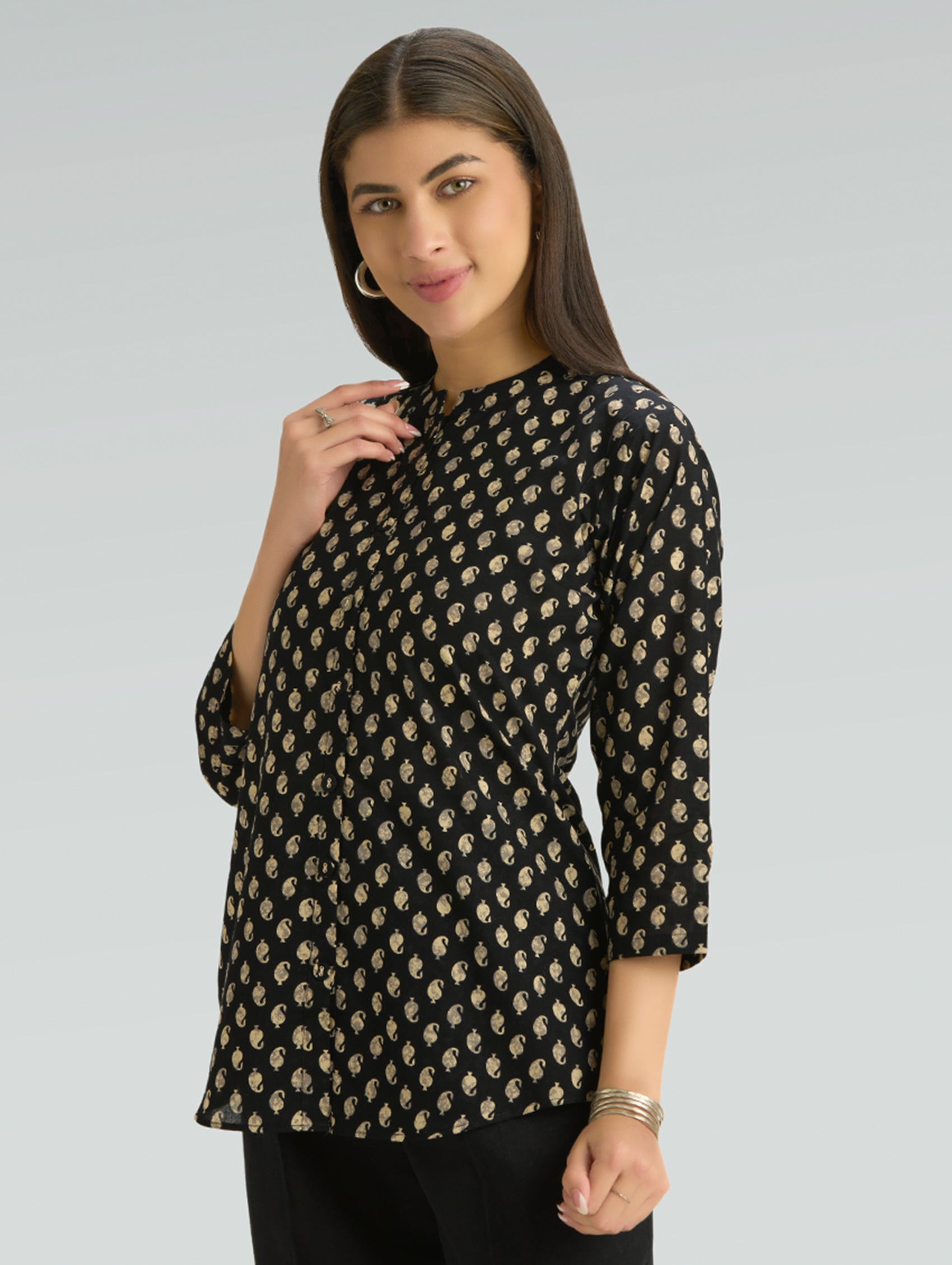 Woman wearing a black patterned top against a gray background
