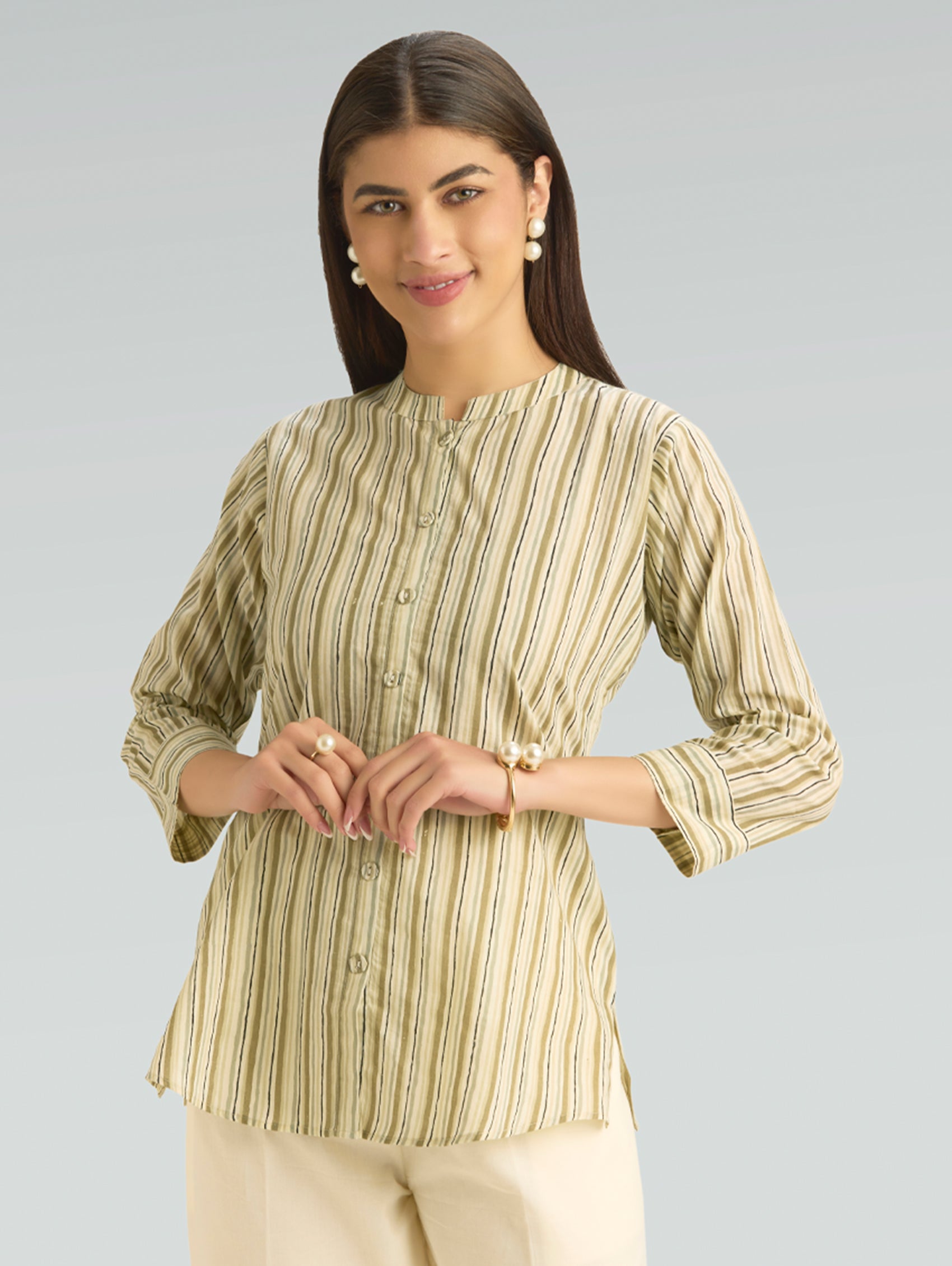 Woman wearing a green and beige striped shirt against a gray background