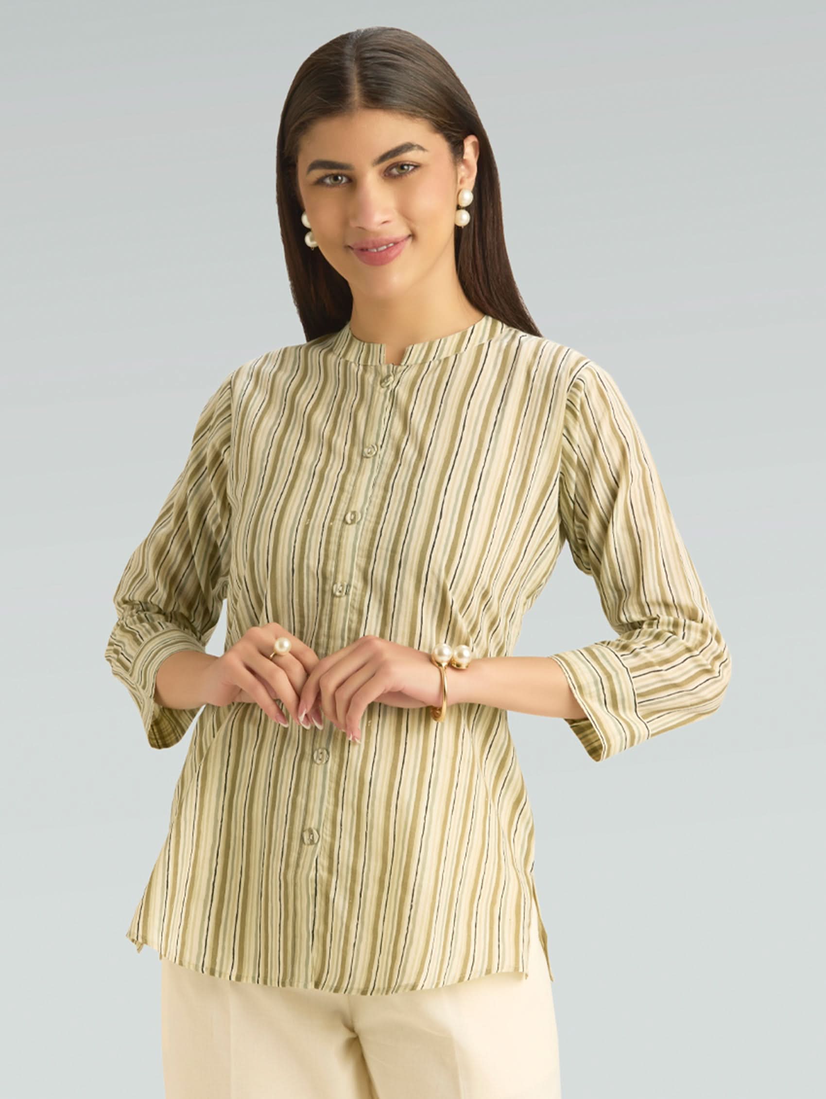 Woman wearing a green and beige striped shirt against a gray background