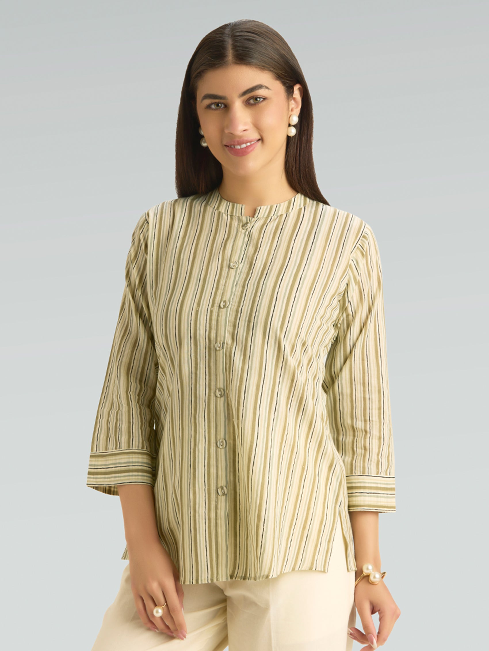 Woman wearing a green and beige striped shirt against a gray background