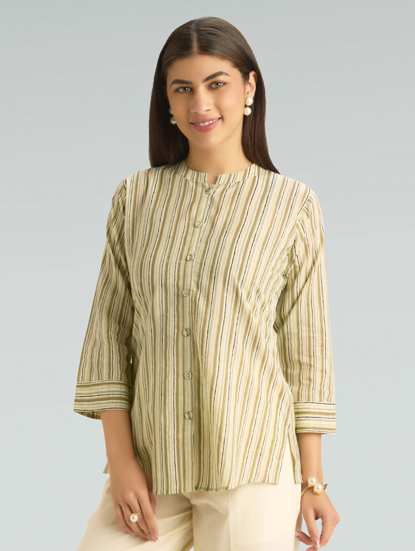 Woman wearing a green and beige striped shirt against a gray background