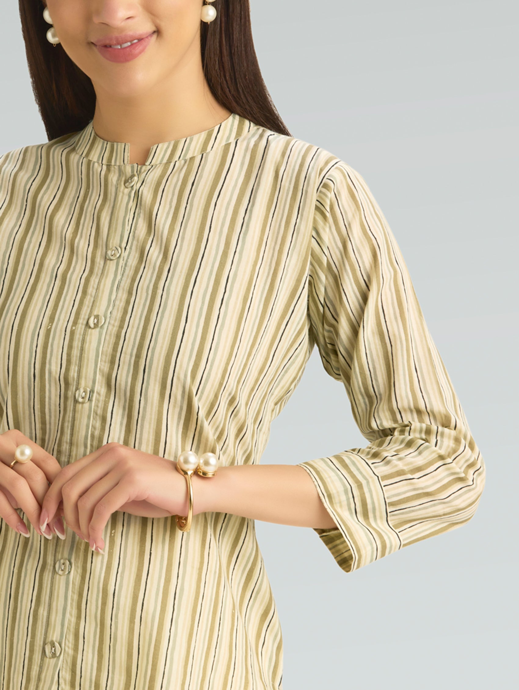 Woman wearing a green and beige striped dress with a plain background