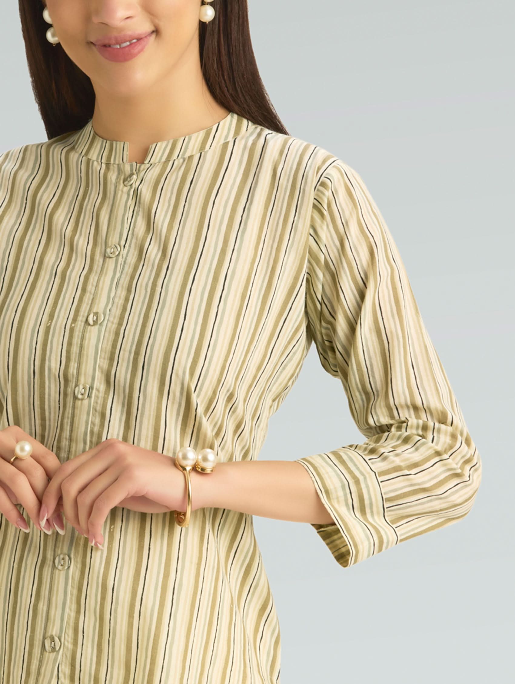 Woman wearing a green and beige striped dress with a plain background