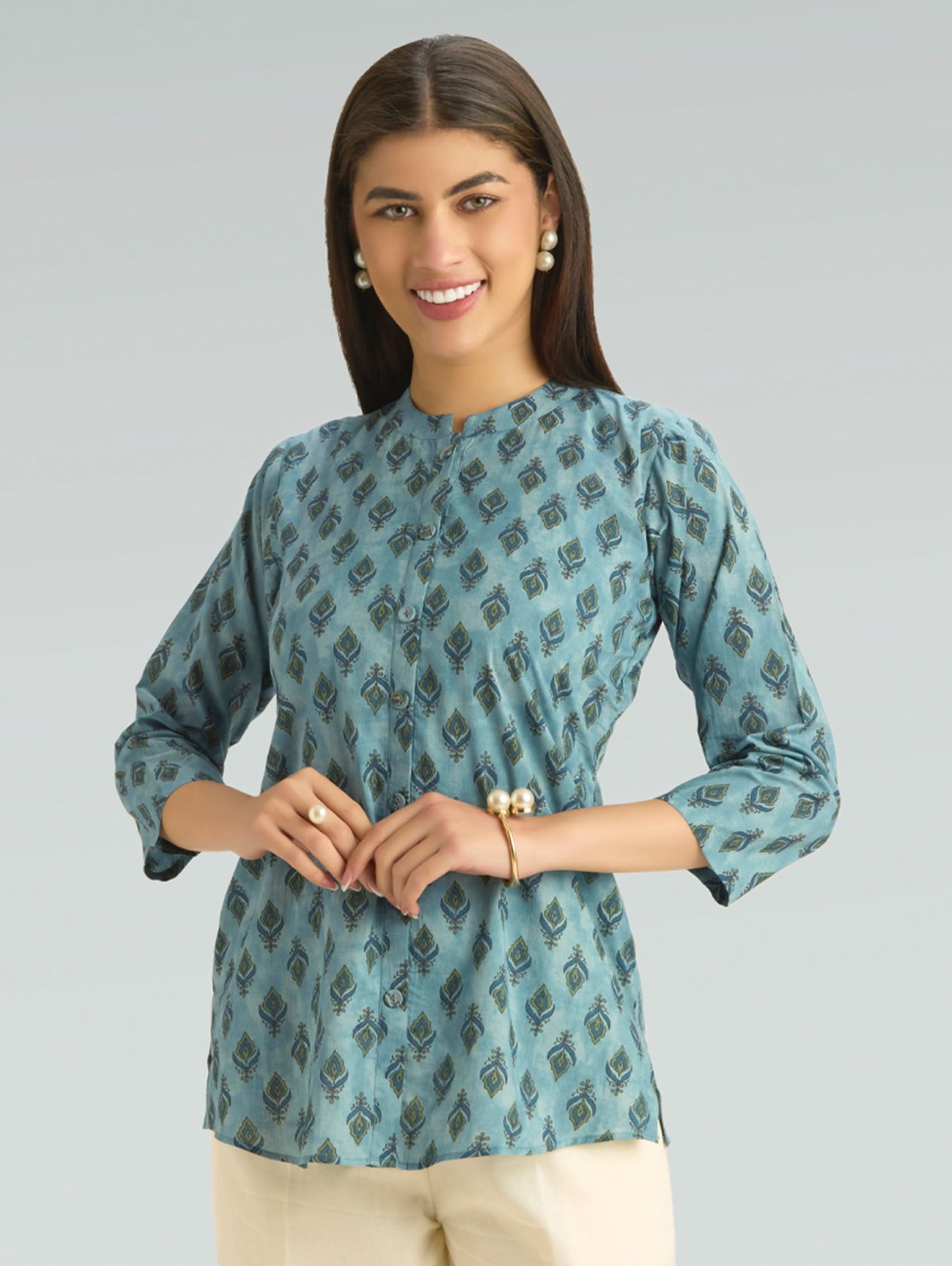 Woman wearing a blue patterned top against a gray background