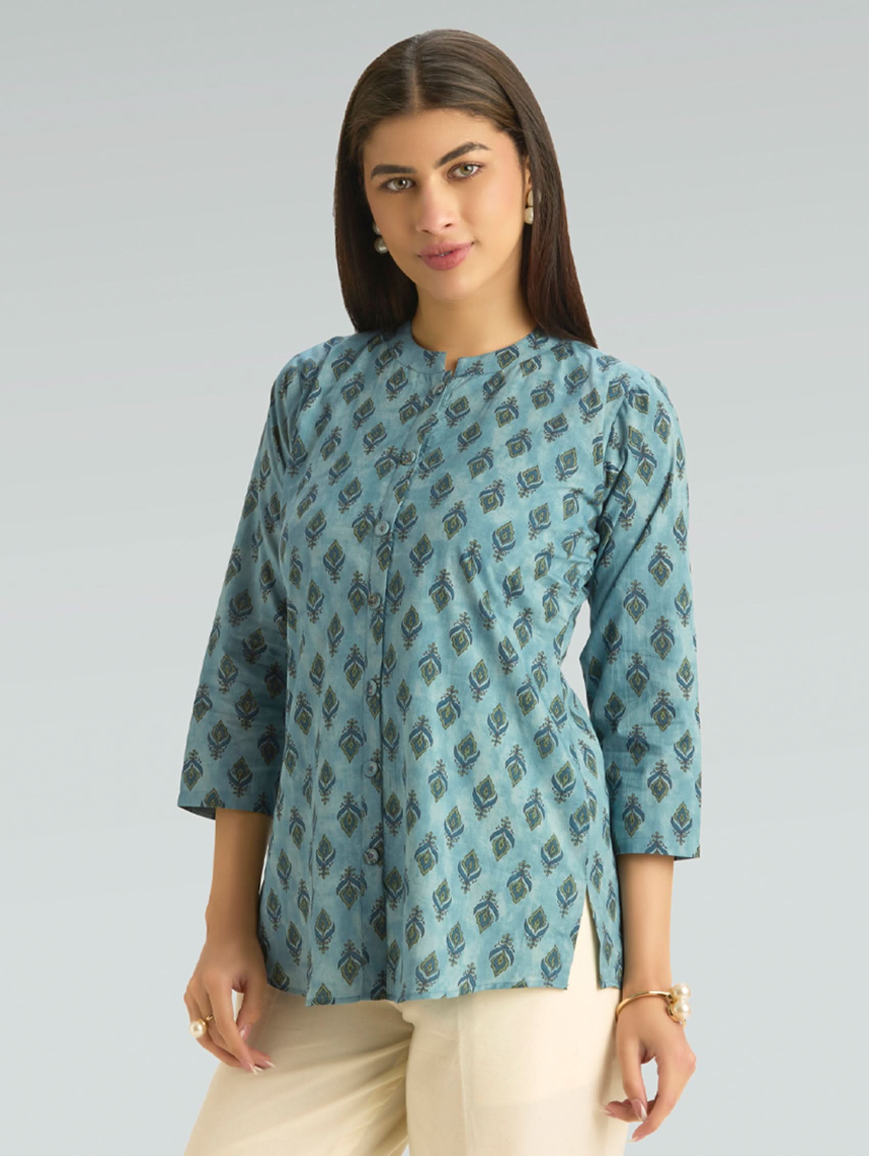 Woman wearing a blue patterned top against a gray background