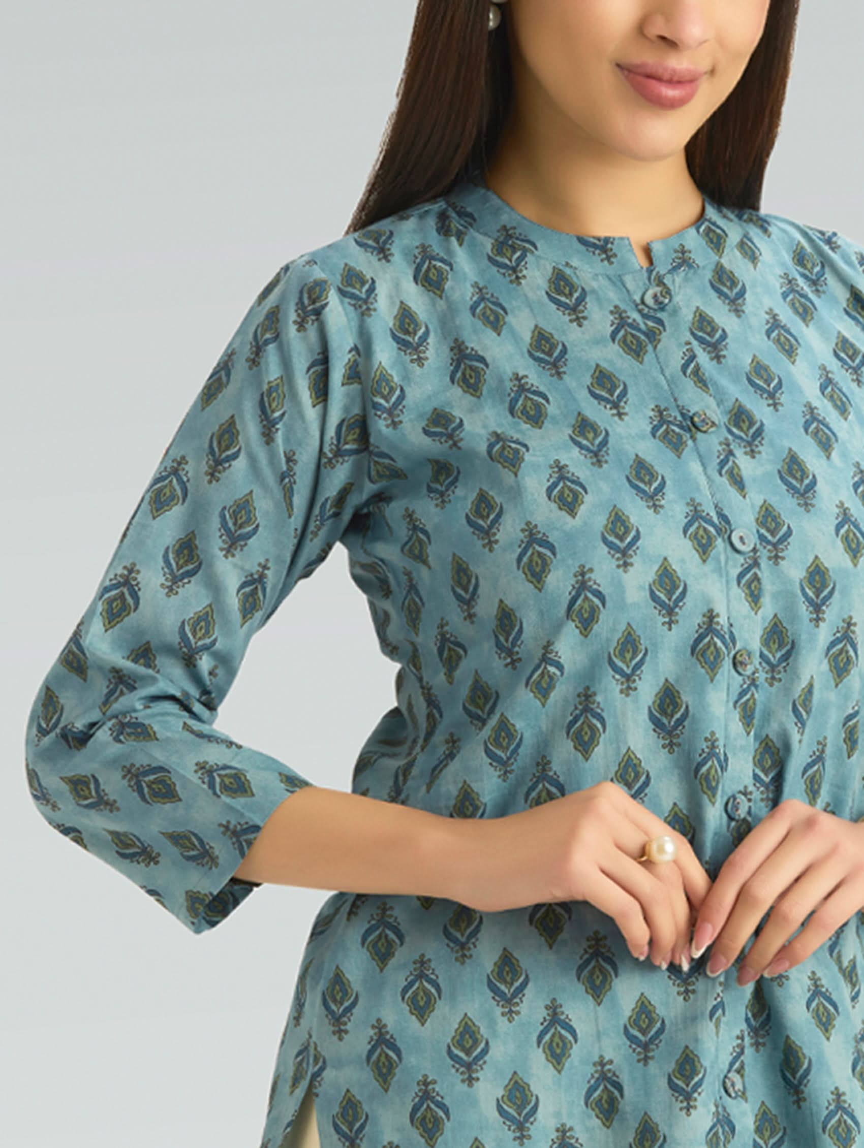 Woman wearing a blue patterned dress against a gray background