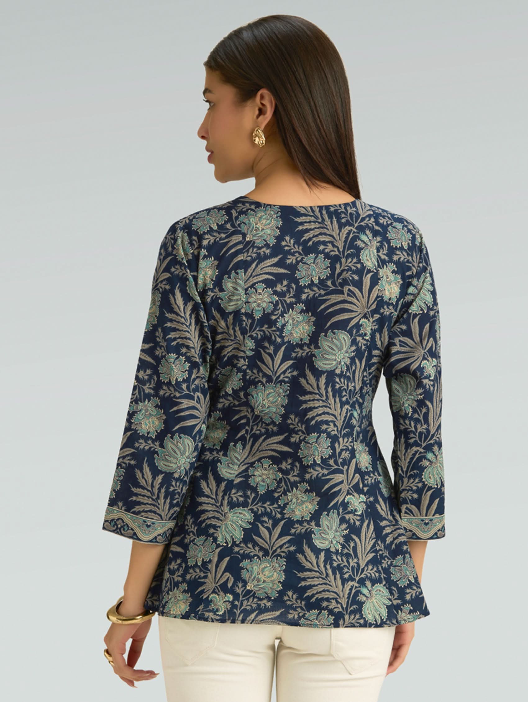 Woman wearing a navy floral patterned top against a gray background