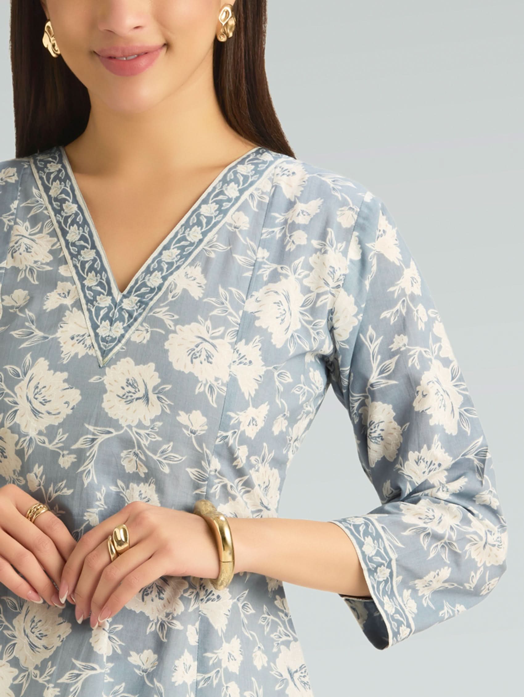 Woman wearing a light blue floral patterned kurta on a gray background