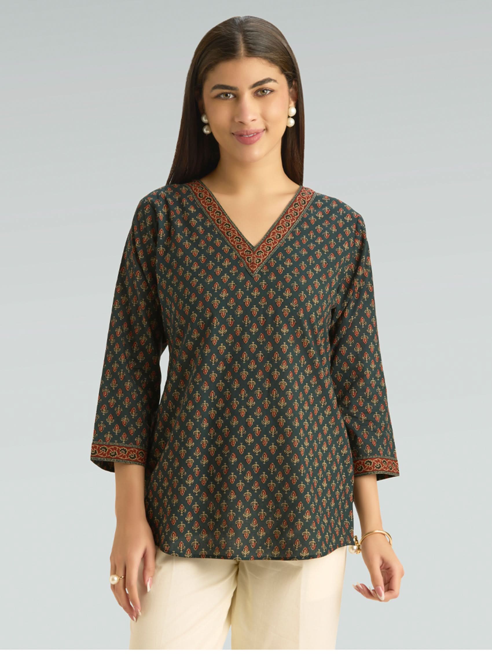 Woman wearing a patterned blouse against a plain background