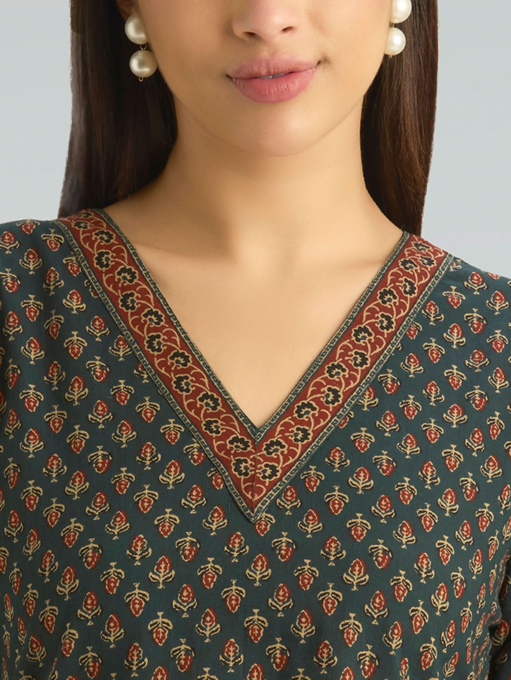 Close-up of a person wearing a patterned top with a neutral background
