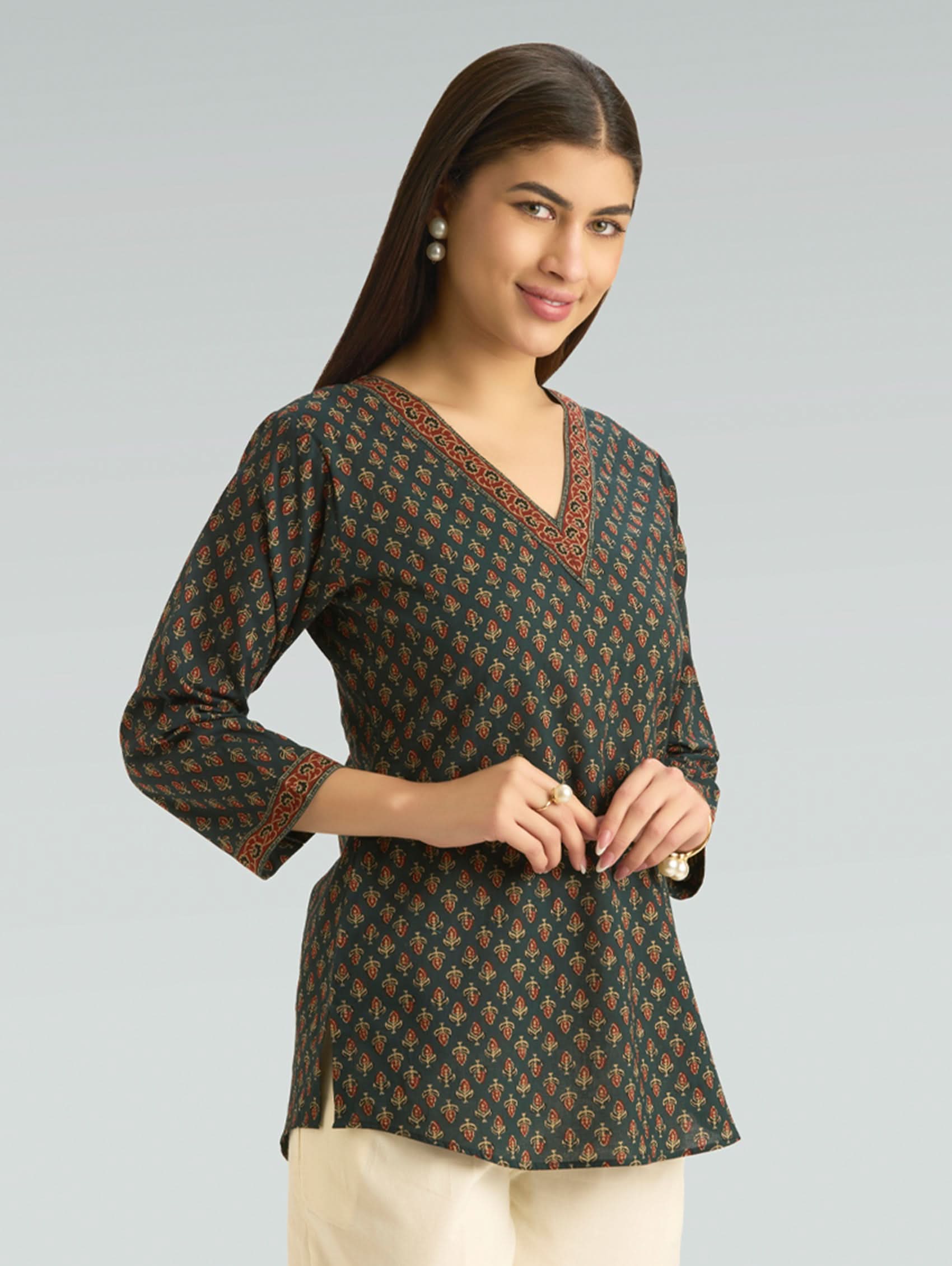 Woman wearing a patterned long-sleeve top against a gray background