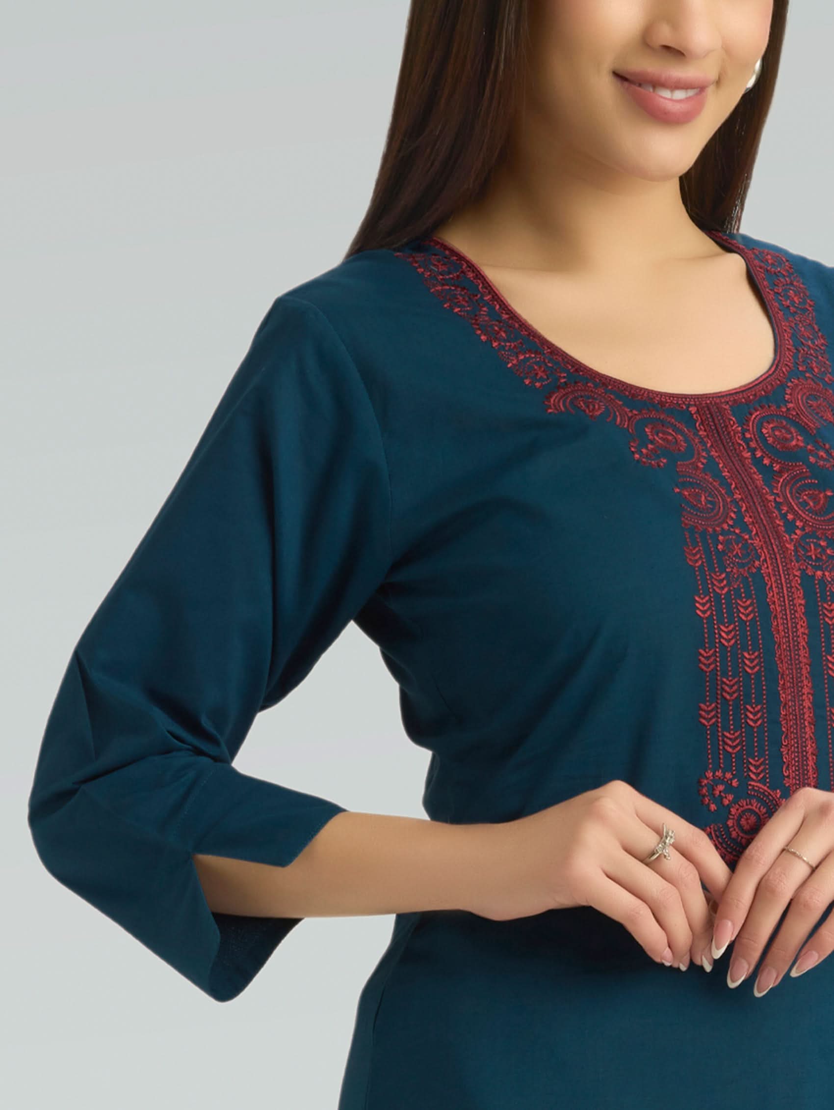 Teal dress with red embroidery on a plain background