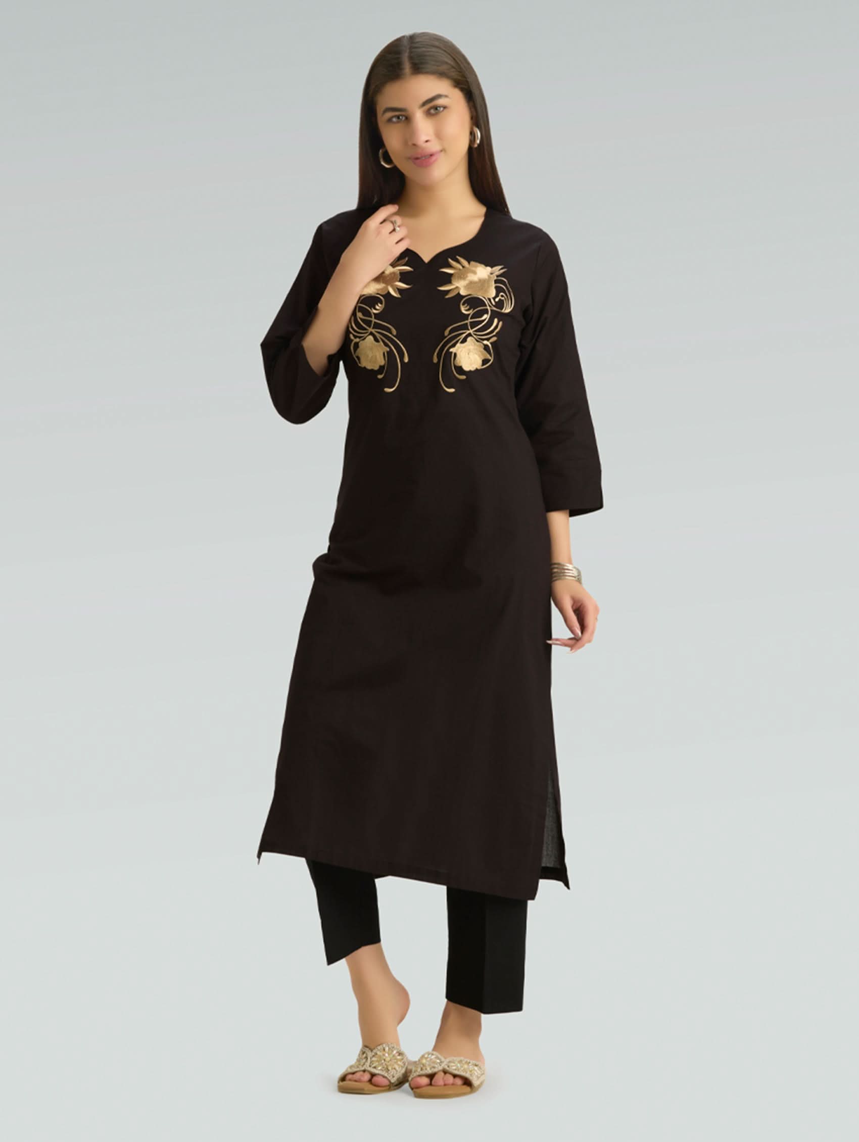 Woman wearing a black kurta with gold embroidery on a gray background