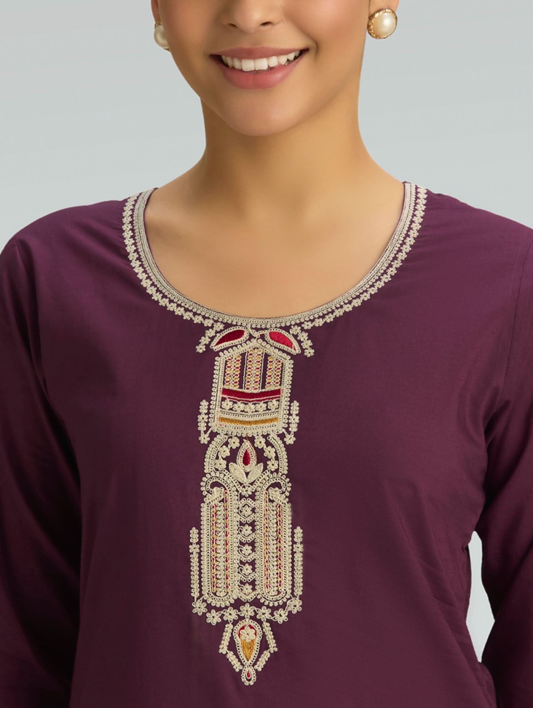 Purple top with intricate white embroidery on a plain background
