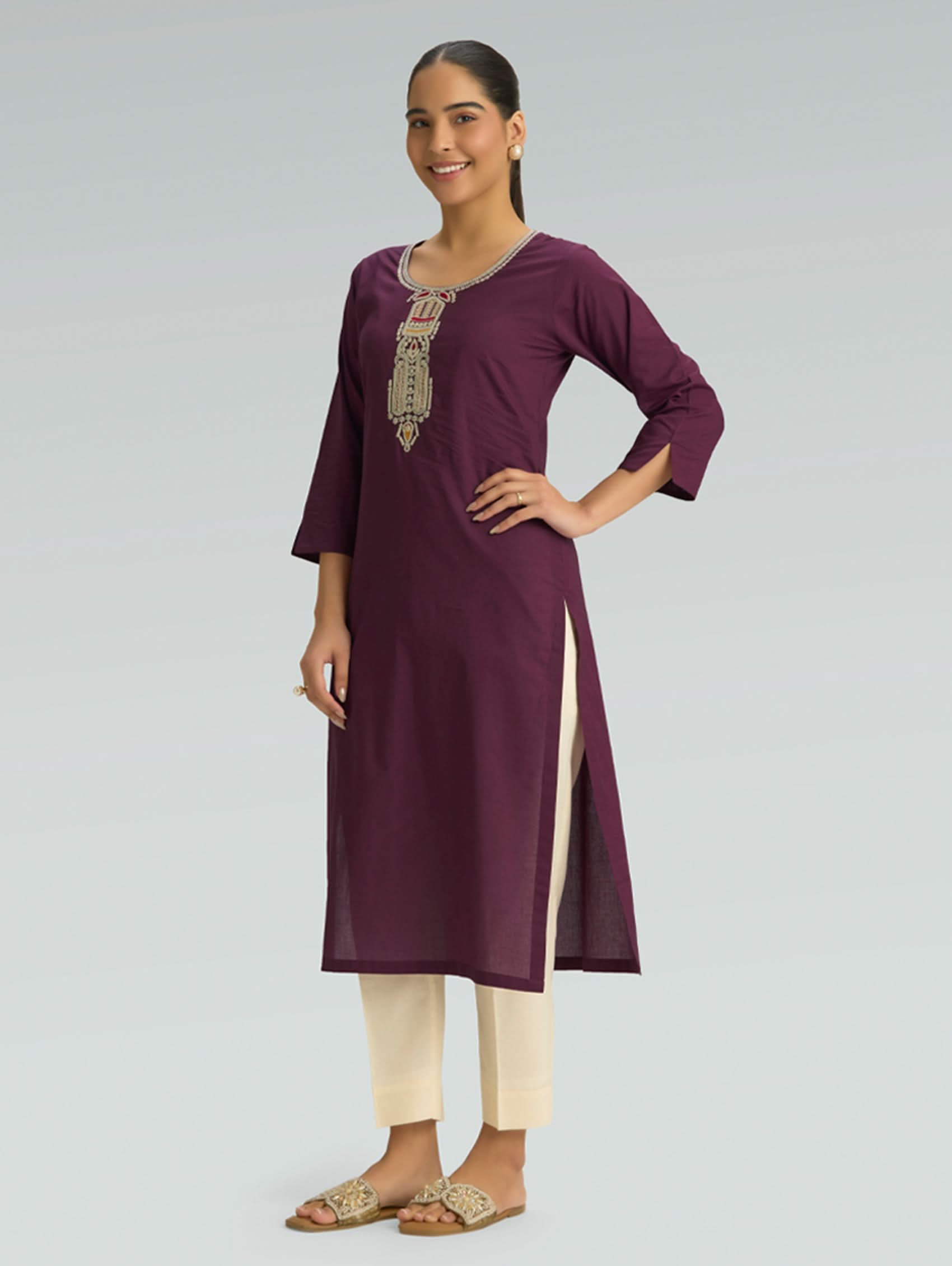 Woman wearing a purple kurta with white pants on a gray background