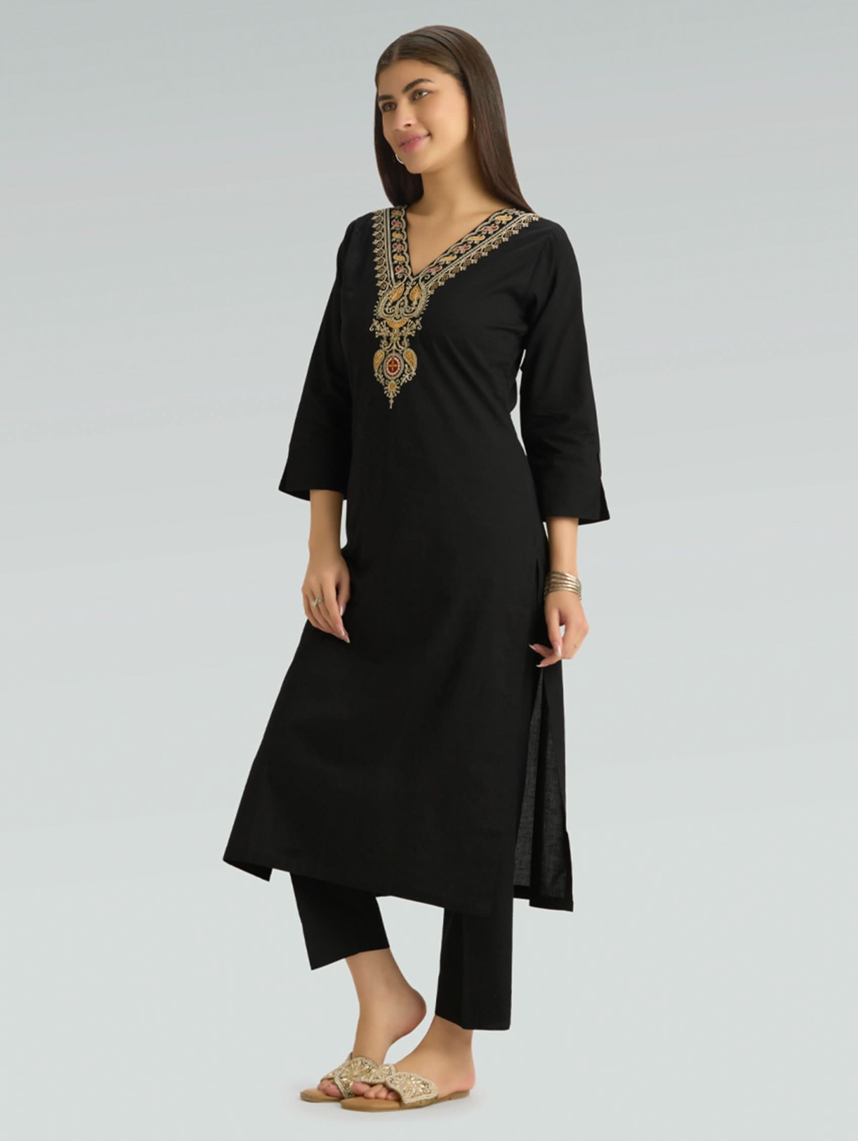 Woman wearing a black kurta with gold embroidery on a gray background