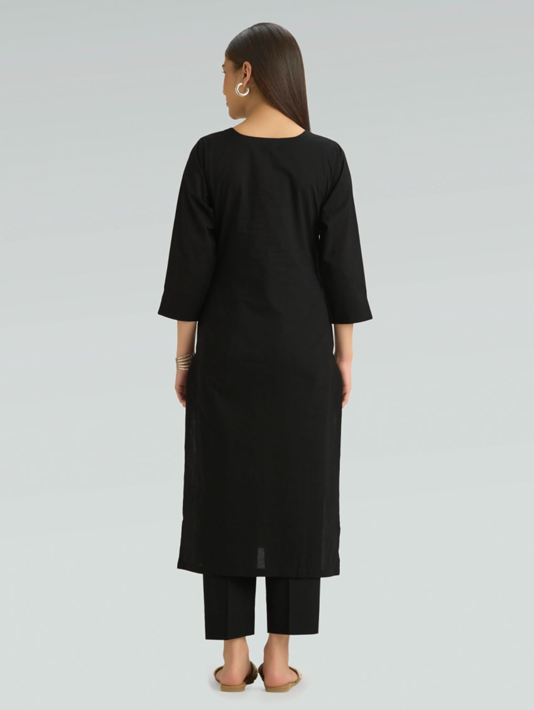 Back view of a woman in a black kurta, elegantly set against a clean, plain background.