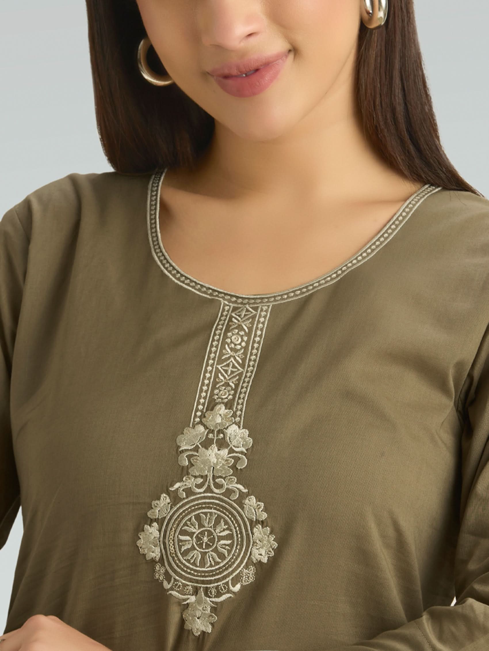 Close-up of a green traditional outfit with intricate silver embroidery on a gray background