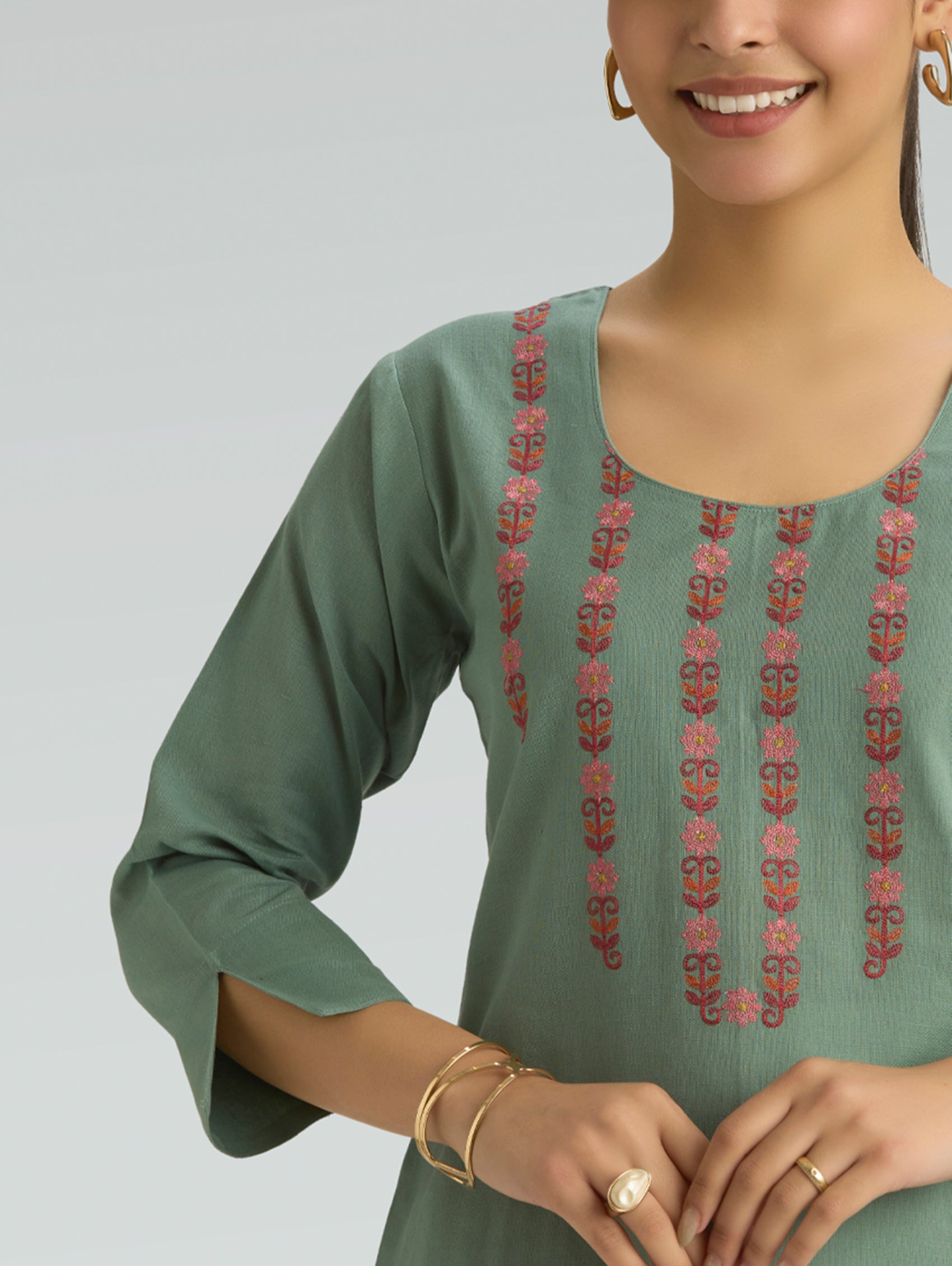 Green embroidered dress worn by a person on a plain background