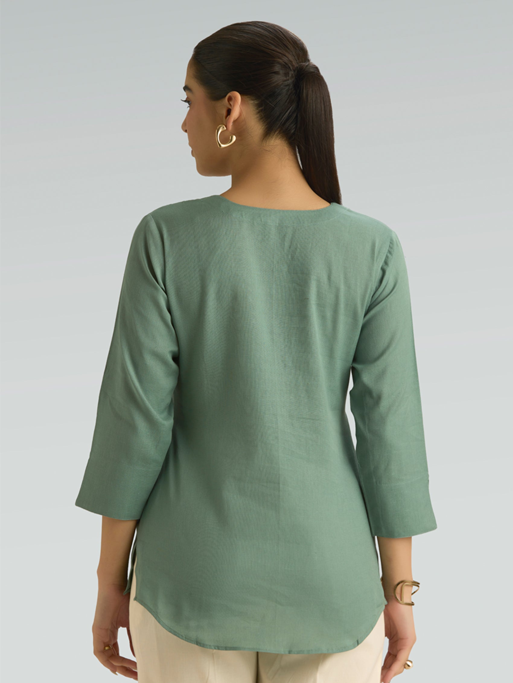Woman wearing a green top with a plain background