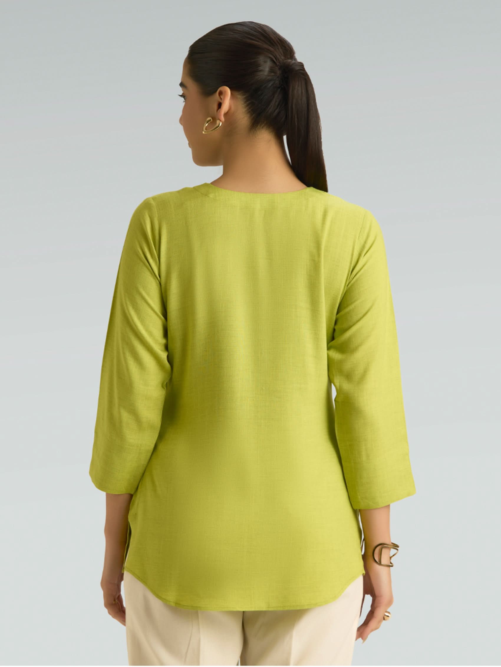 Woman wearing a green top with a plain background