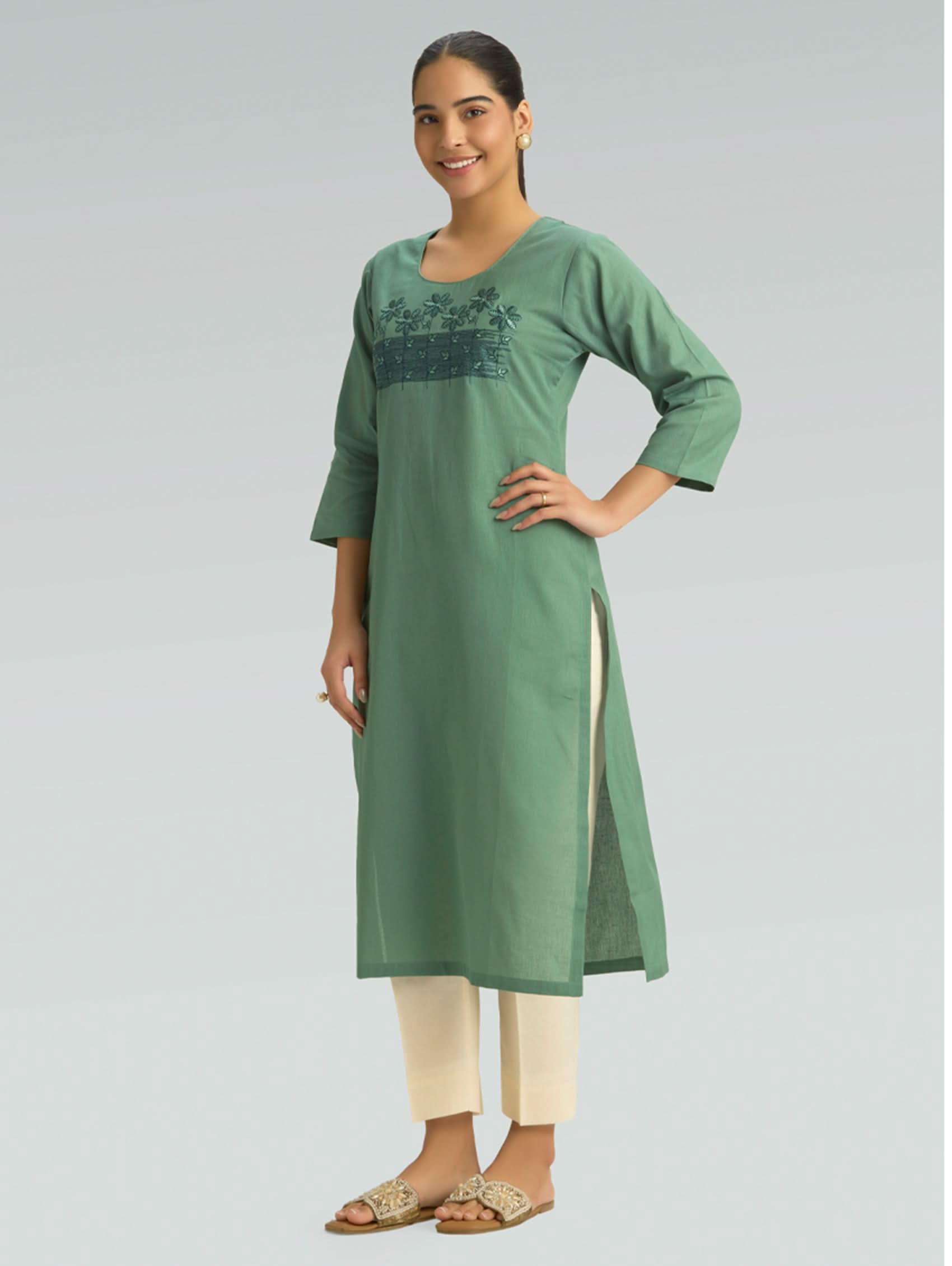 Woman wearing a green kurta with embroidery on a gray background