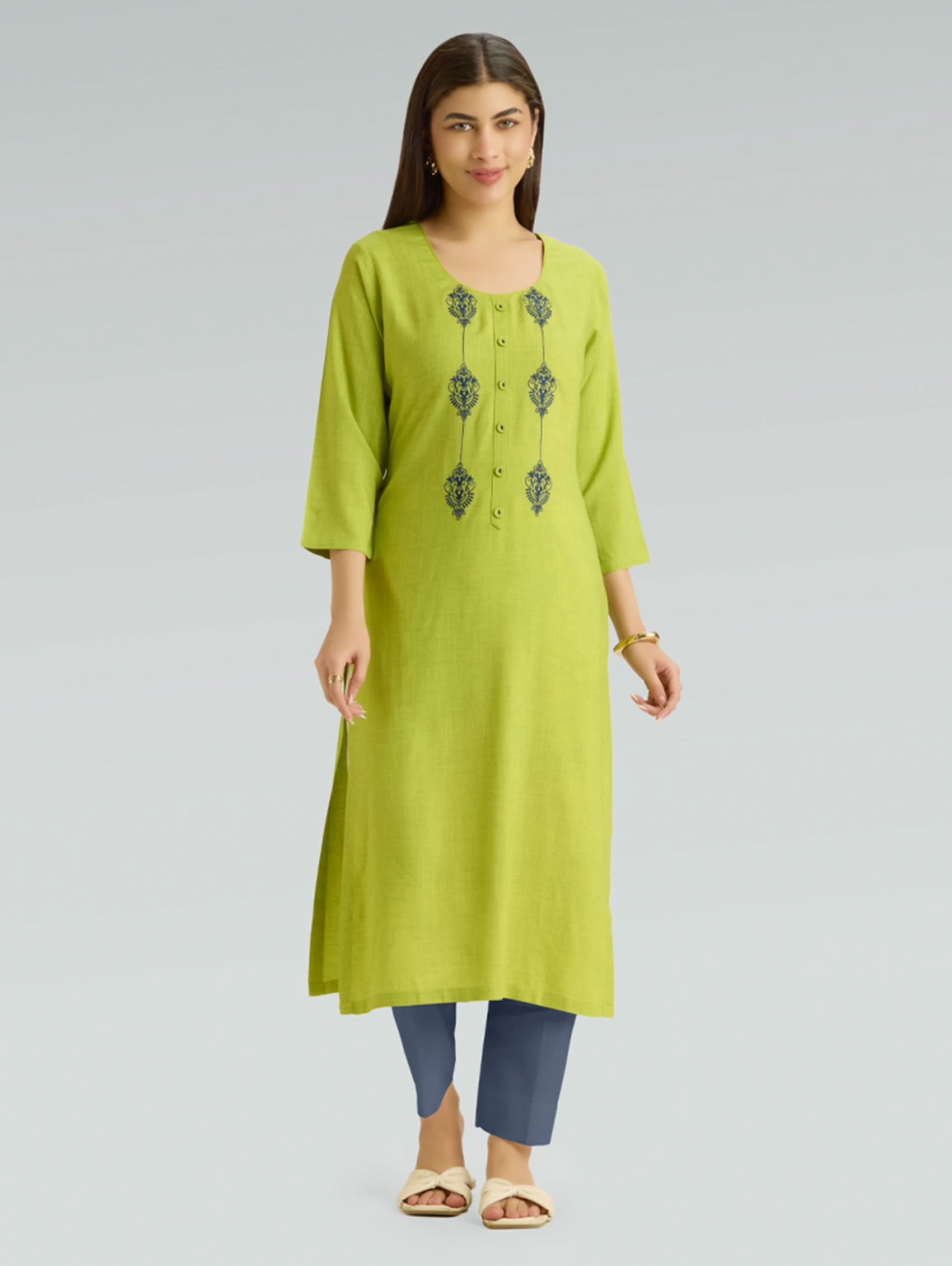 Woman wearing a green kurta with embroidery on a gray background