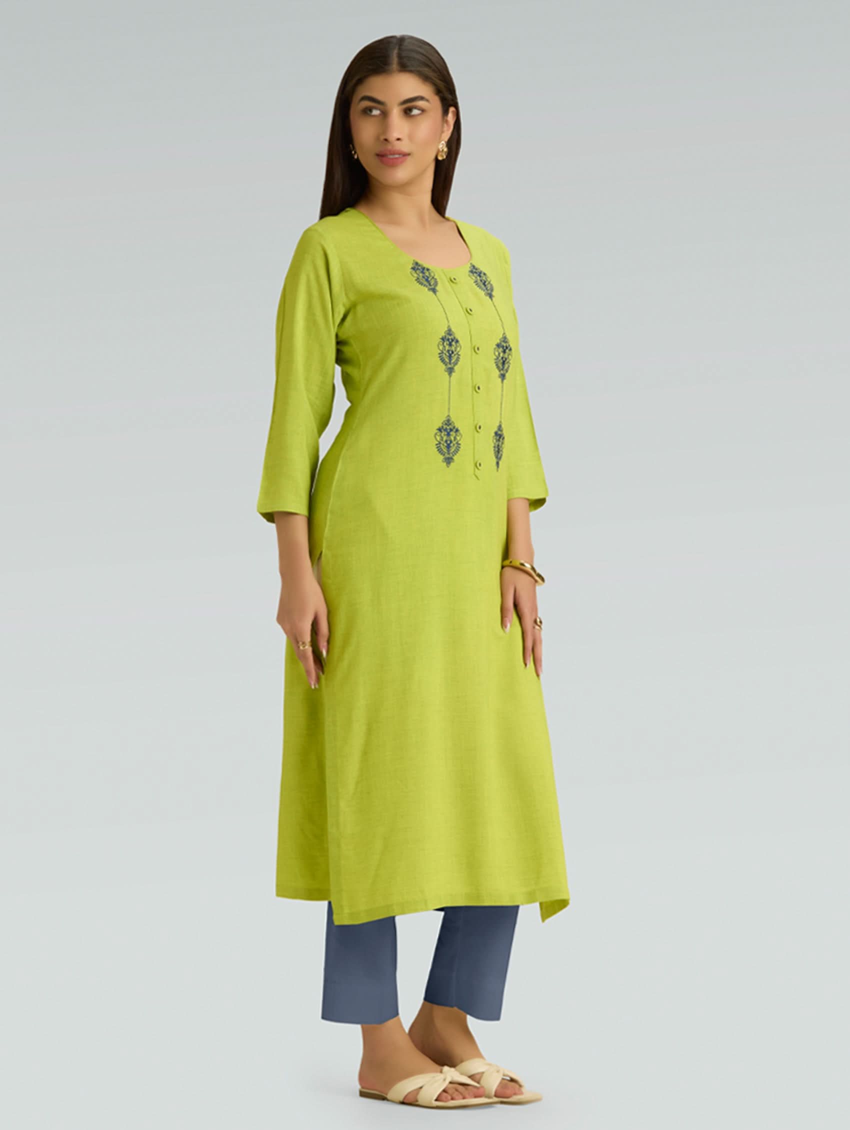 Woman wearing a green kurta with embroidery on a light gray background